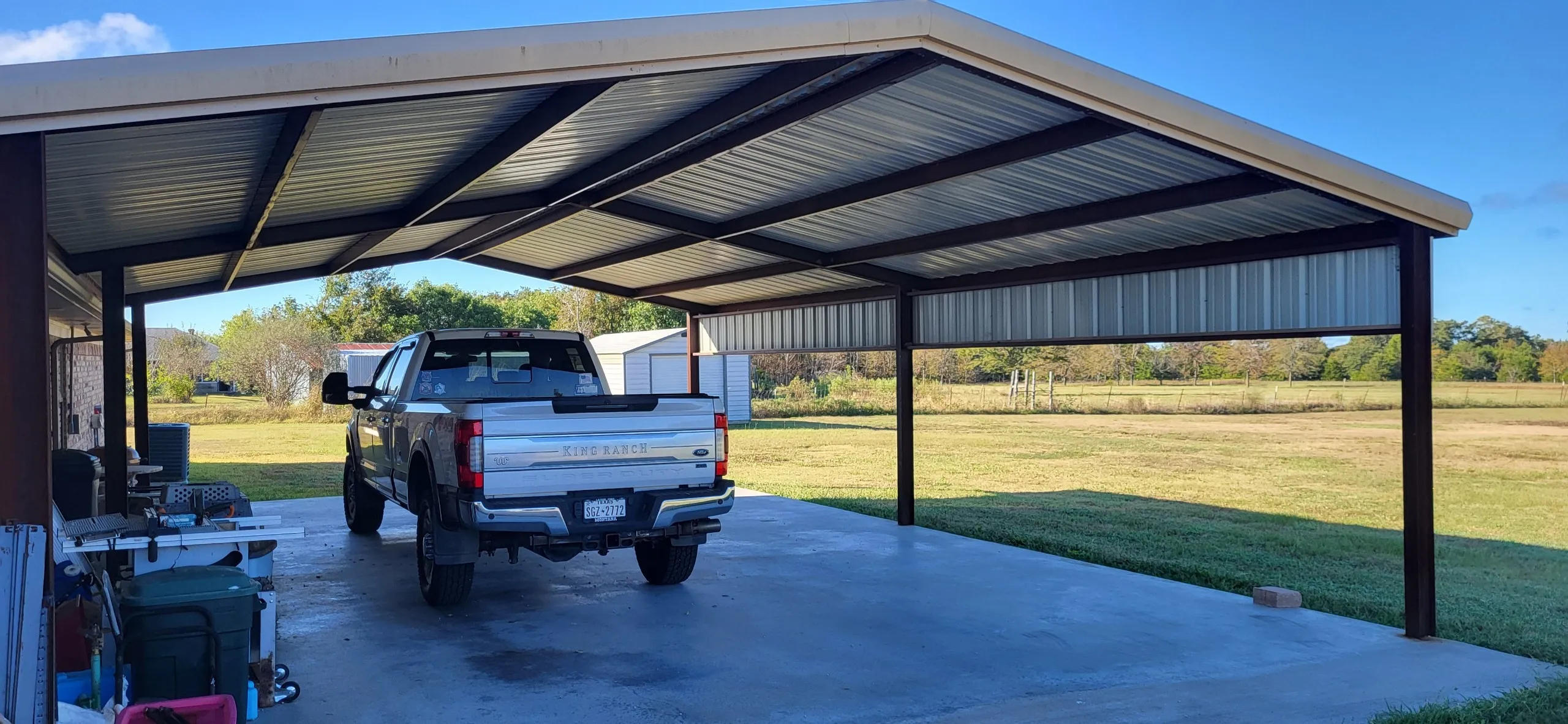 View of parking featuring a garage, a lawn, and a carport