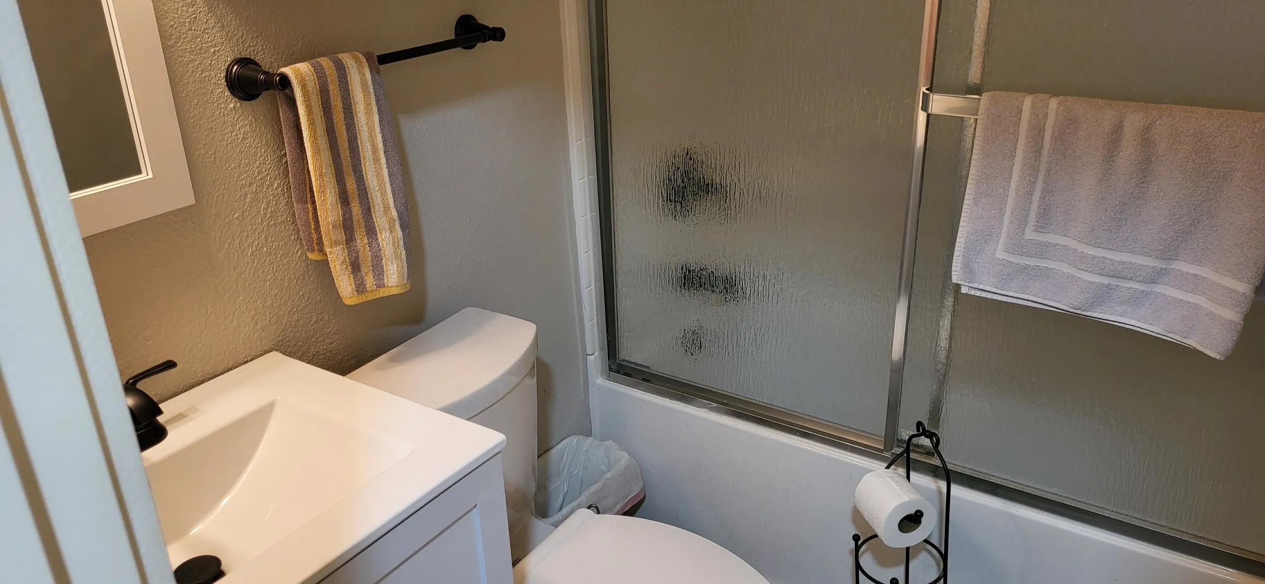 Full bathroom featuring shower / bath combination with glass door, toilet, and vanity