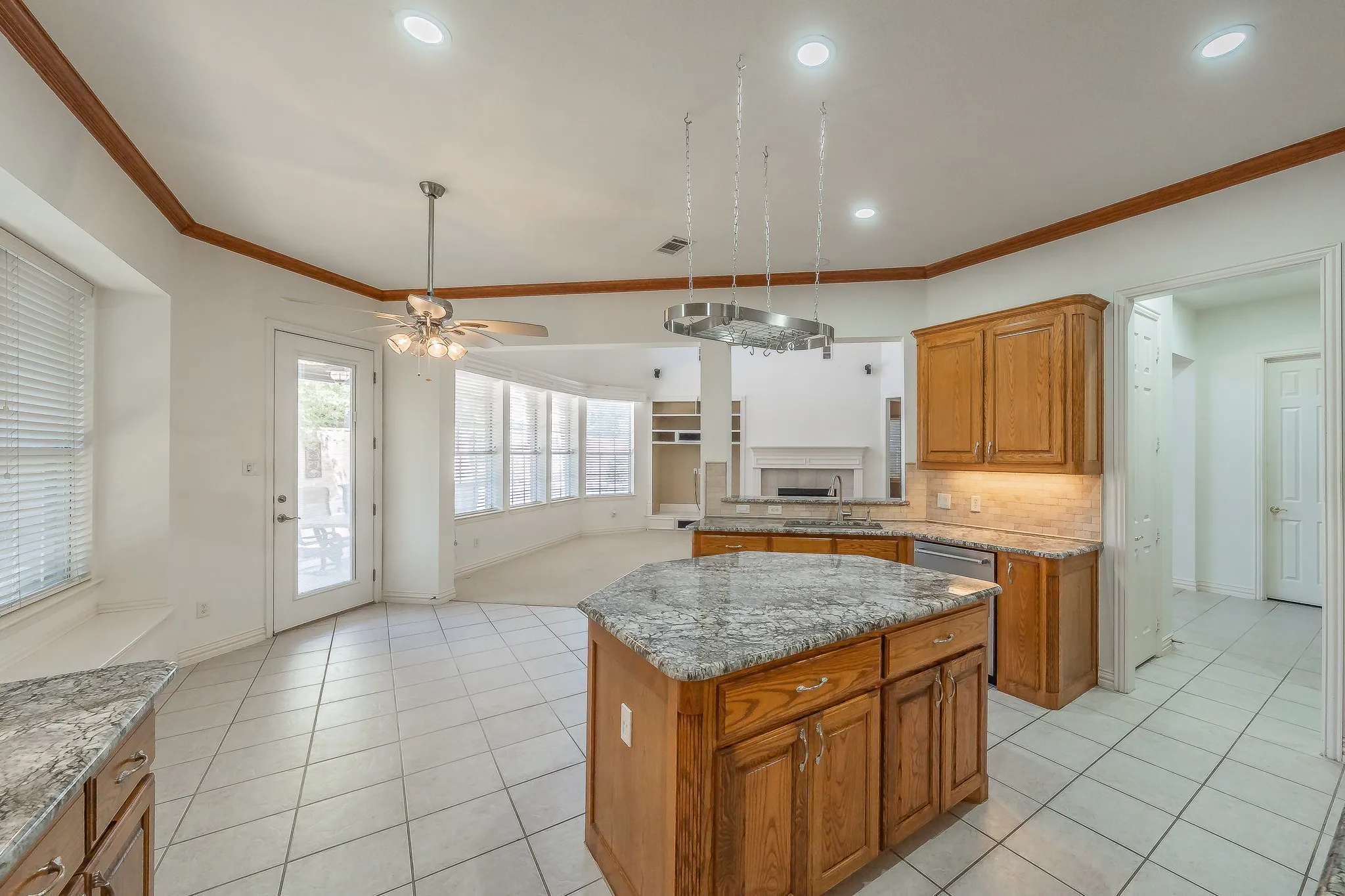 Kitchen featuring a central island with a stone-finish countertop, wood-finish cabinetry, tile flooring, and LED lighting