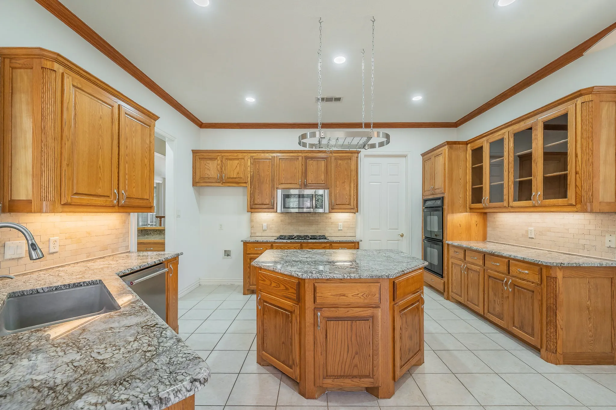 Wood-finish cabinetry, stone countertops, stainless steel appliances, tile flooring, and LED lighting throughout