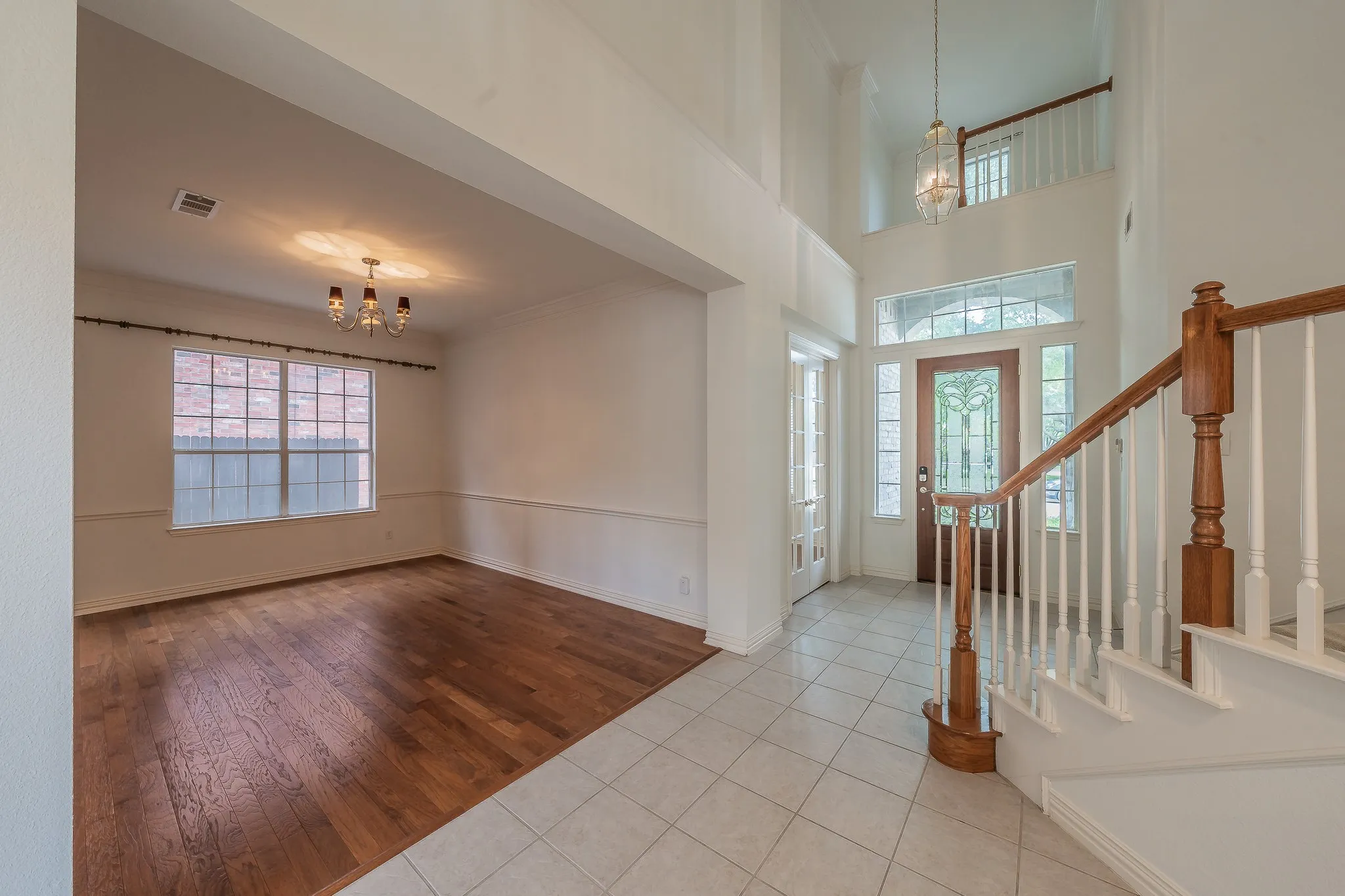 Two-story foyer with tile flooring and a wood staircase featuring white balusters