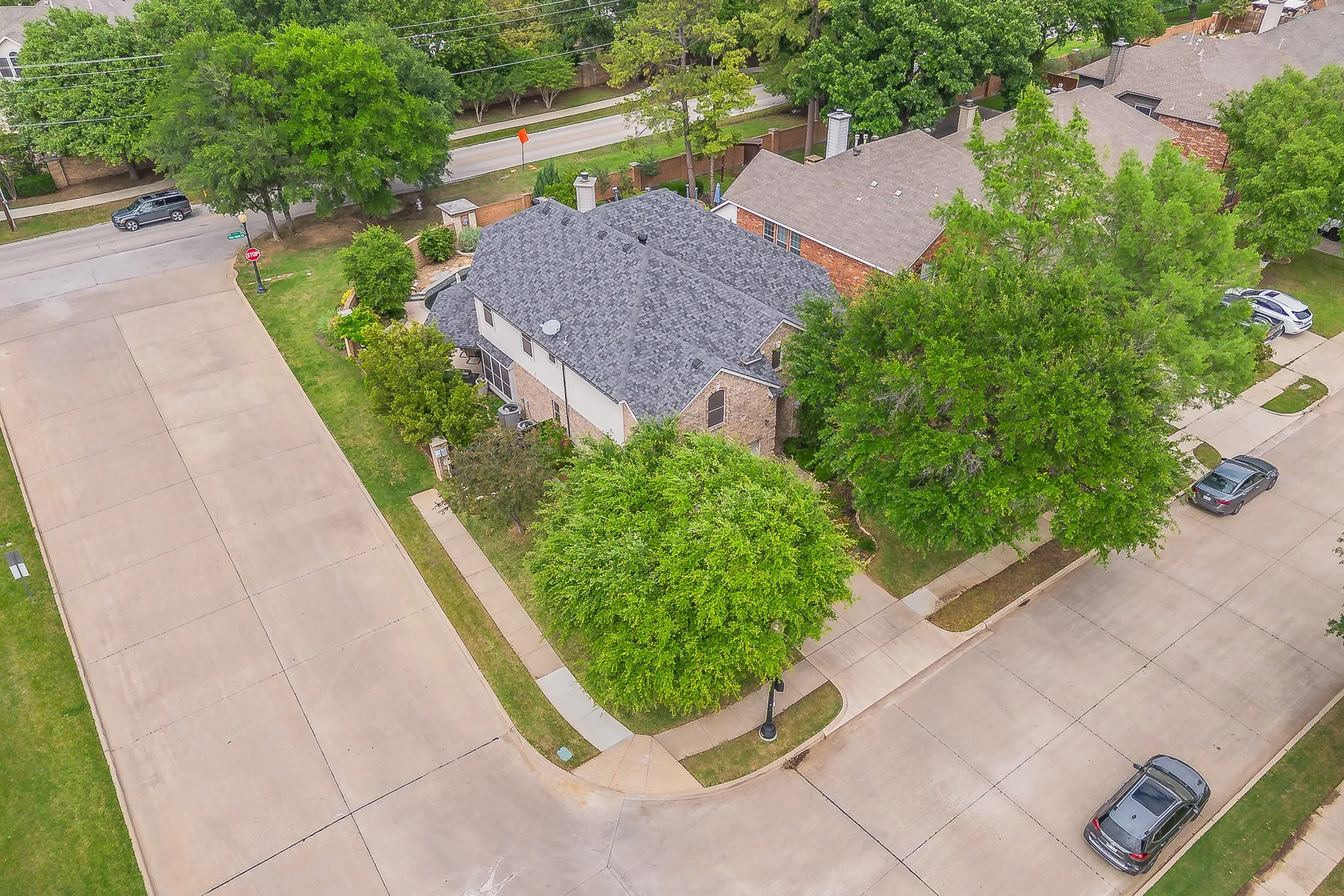 Two-story residence with a gray shingle roof and brick facade