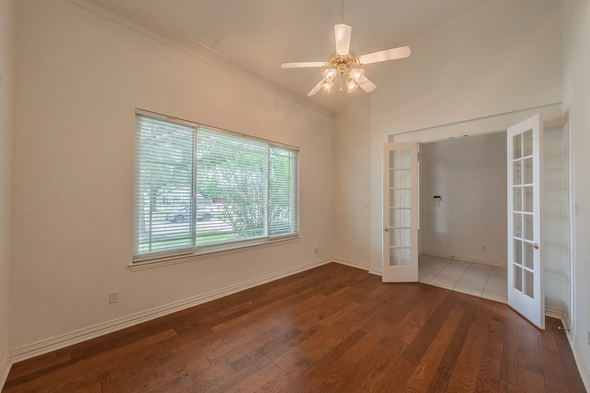 Room featuring wood-finish flooring, a vaulted ceiling, and crown molding