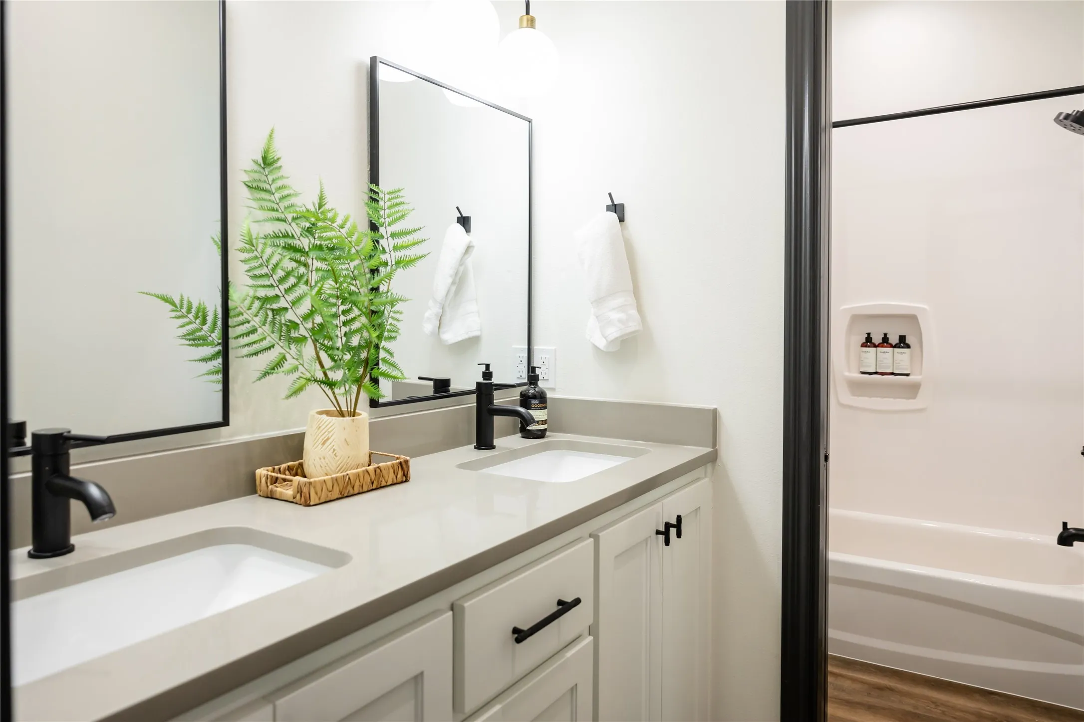 Full bathroom featuring double vanity, bathtub / shower combination, and dark wood-style flooring