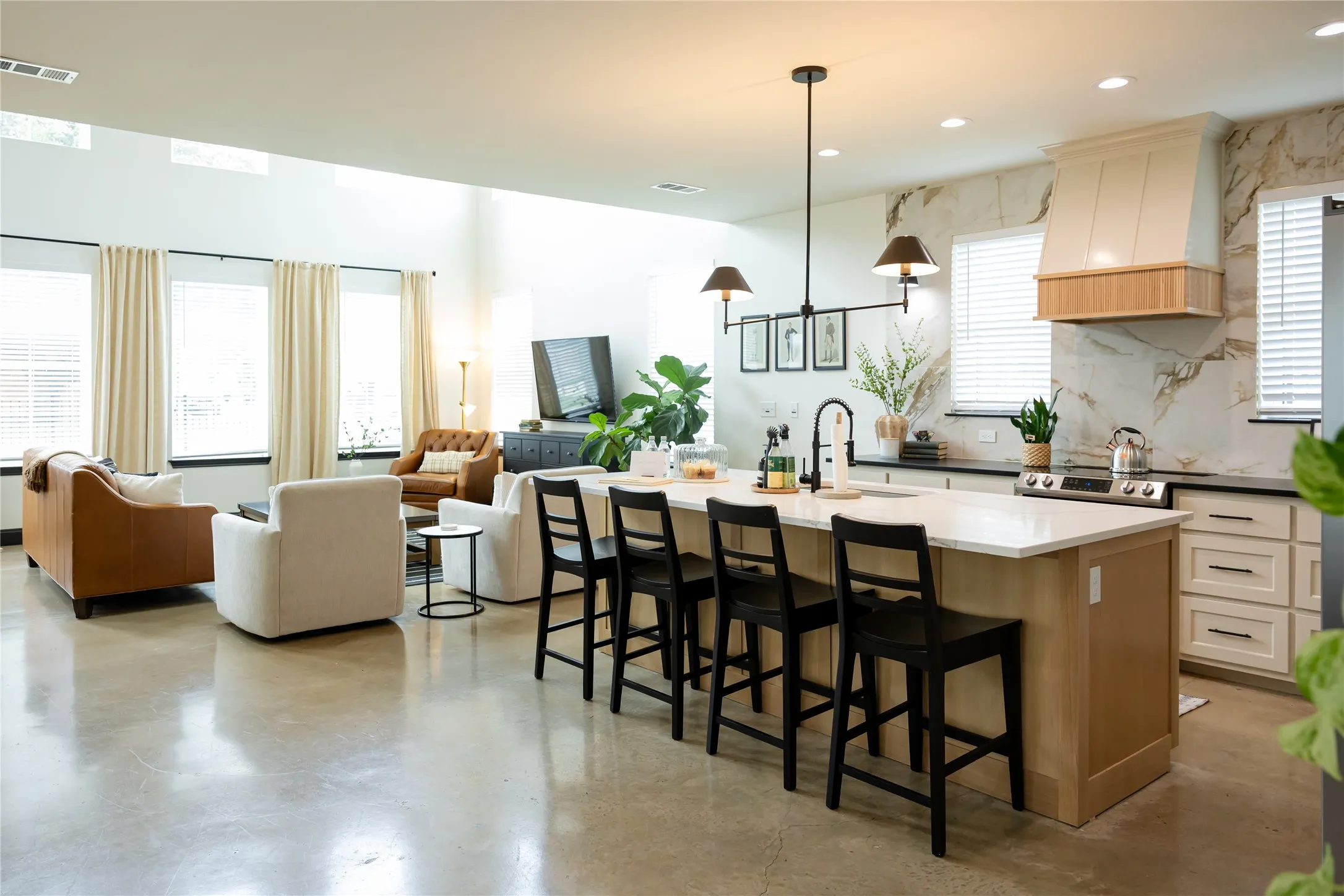 Two tone kitchen featuring finished concrete flooring, a kitchen island with sink, two tone color scheme, a kitchen bar, and backsplash