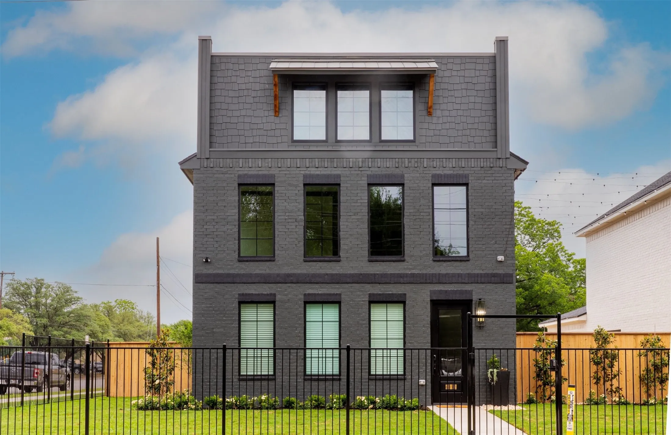 View of front facade featuring brick siding, a fenced front yard, and a gate