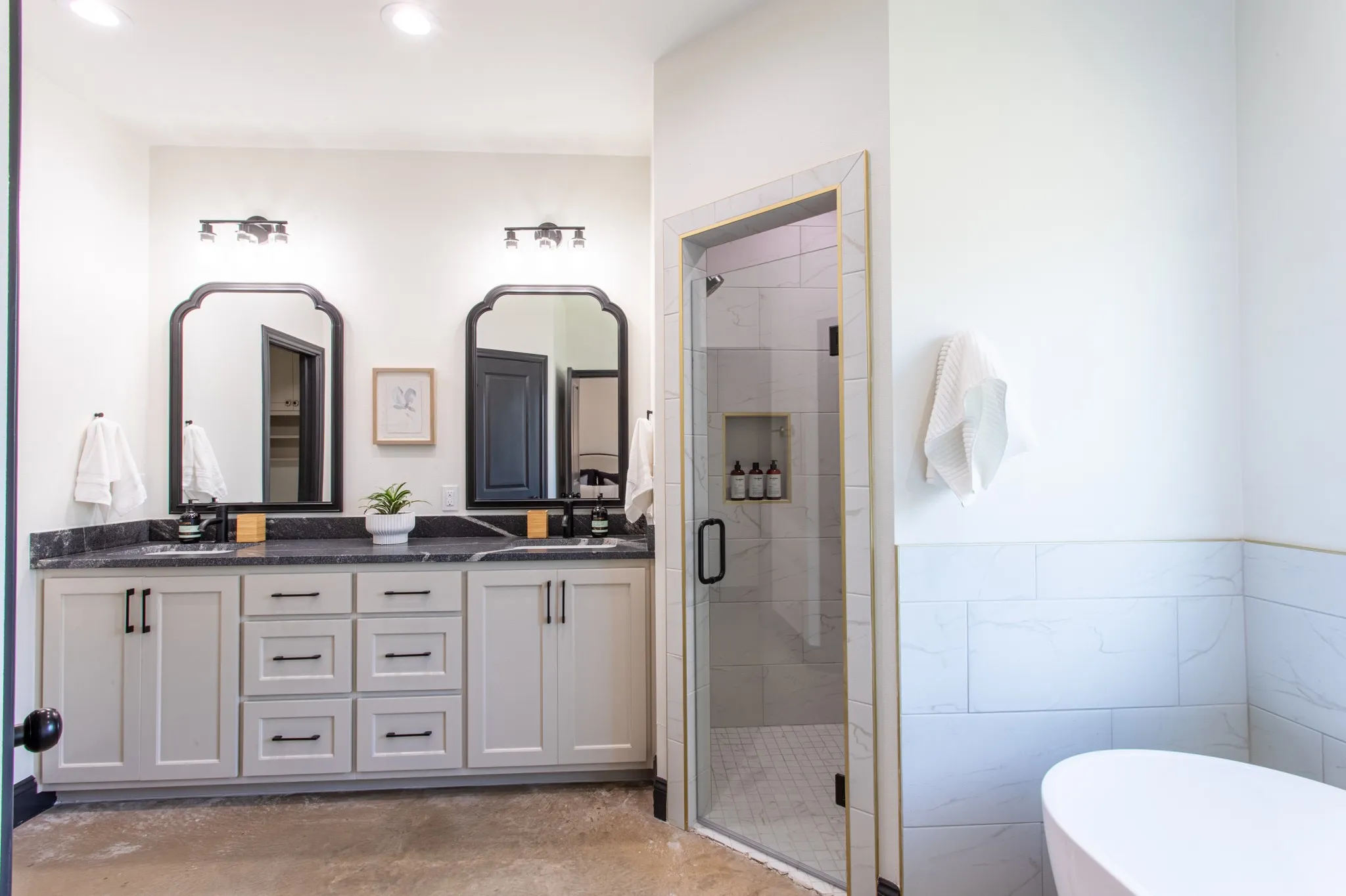 Full bathroom featuring a shower stall, double vanity, a freestanding tub, and concrete floors