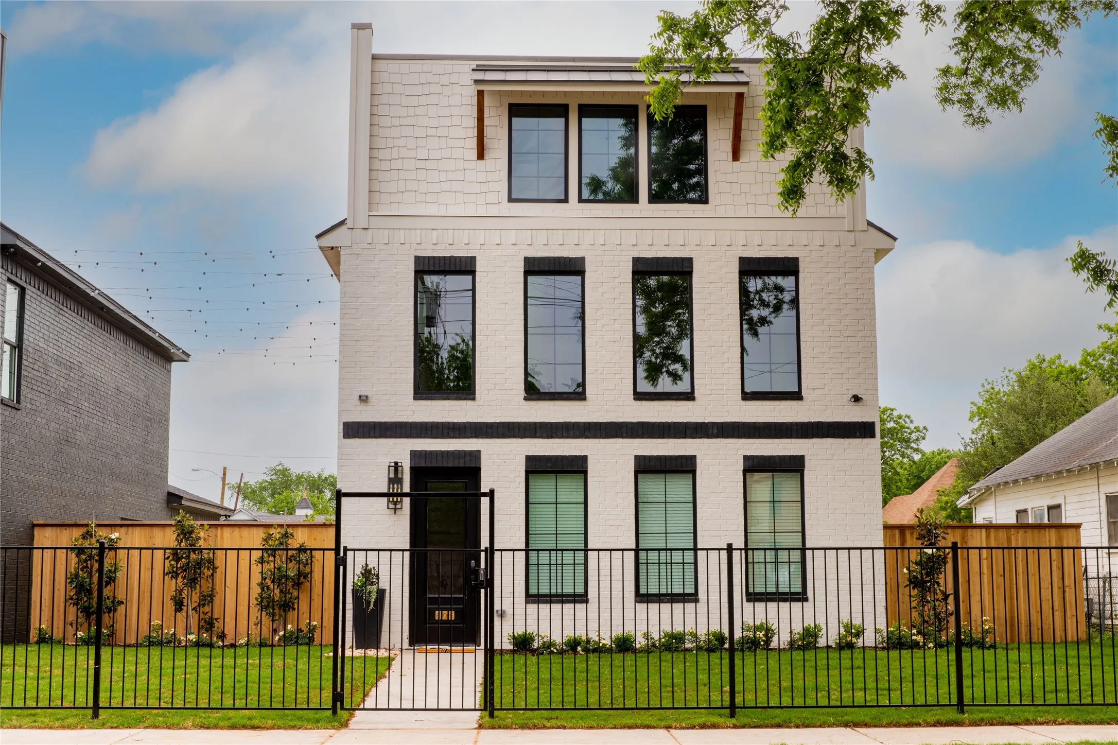 Contemporary home featuring a gate, brick siding, and a fenced front yard