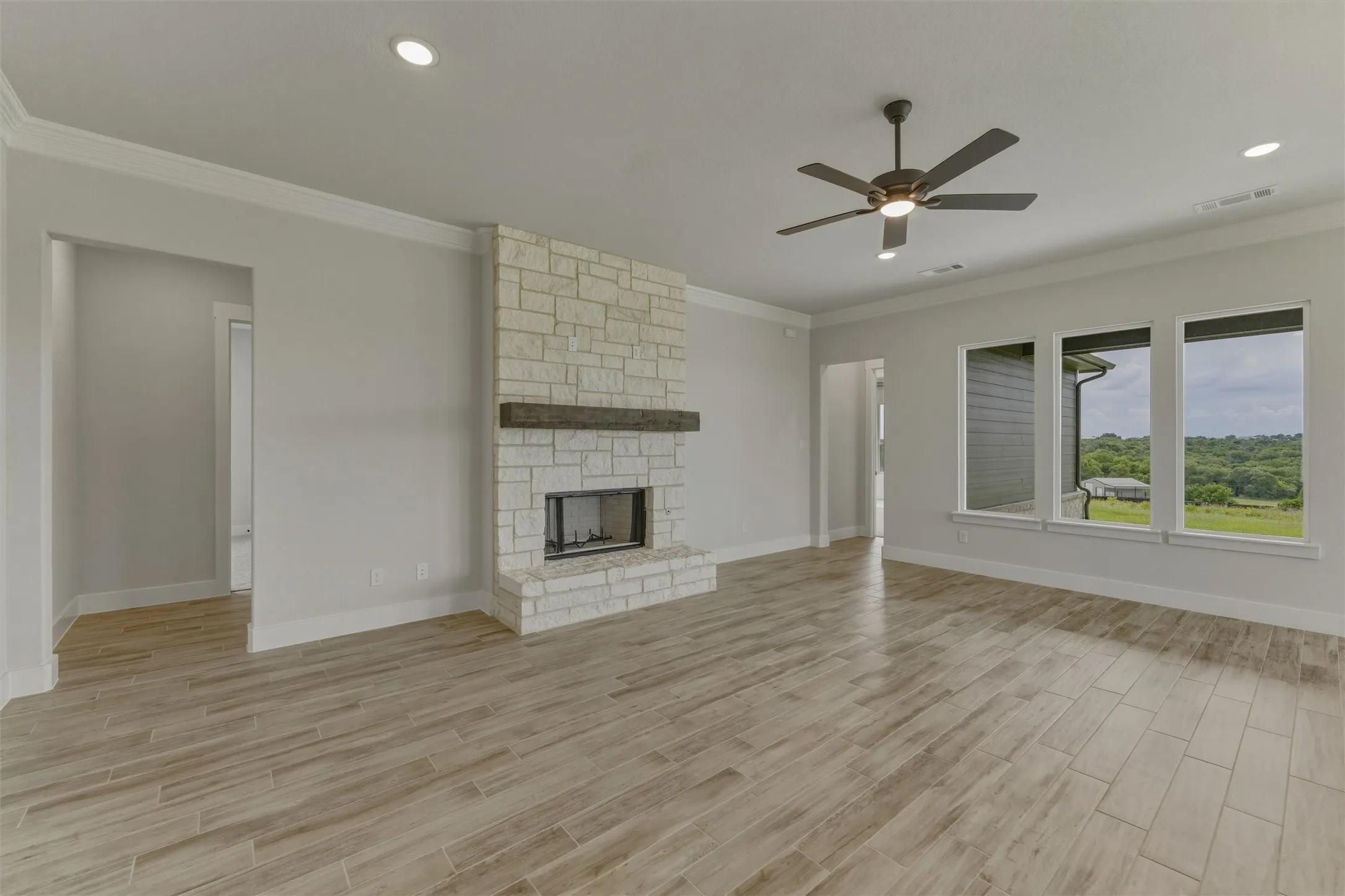 Expansive living area featuring a stacked stone fireplace with a substantial wood mantel