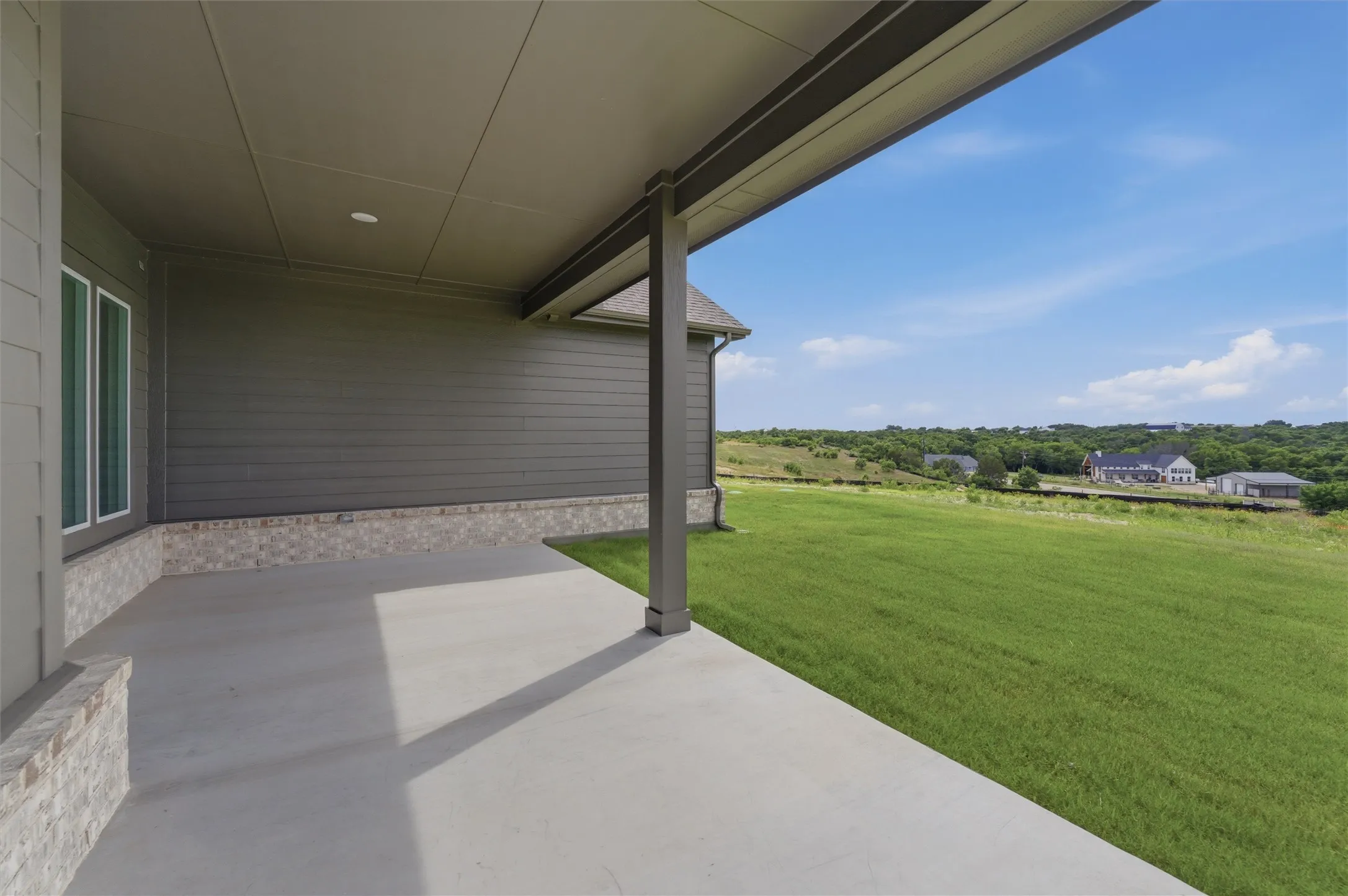 Covered concrete patio featuring recessed lighting, a stone veneer base, and durable siding
