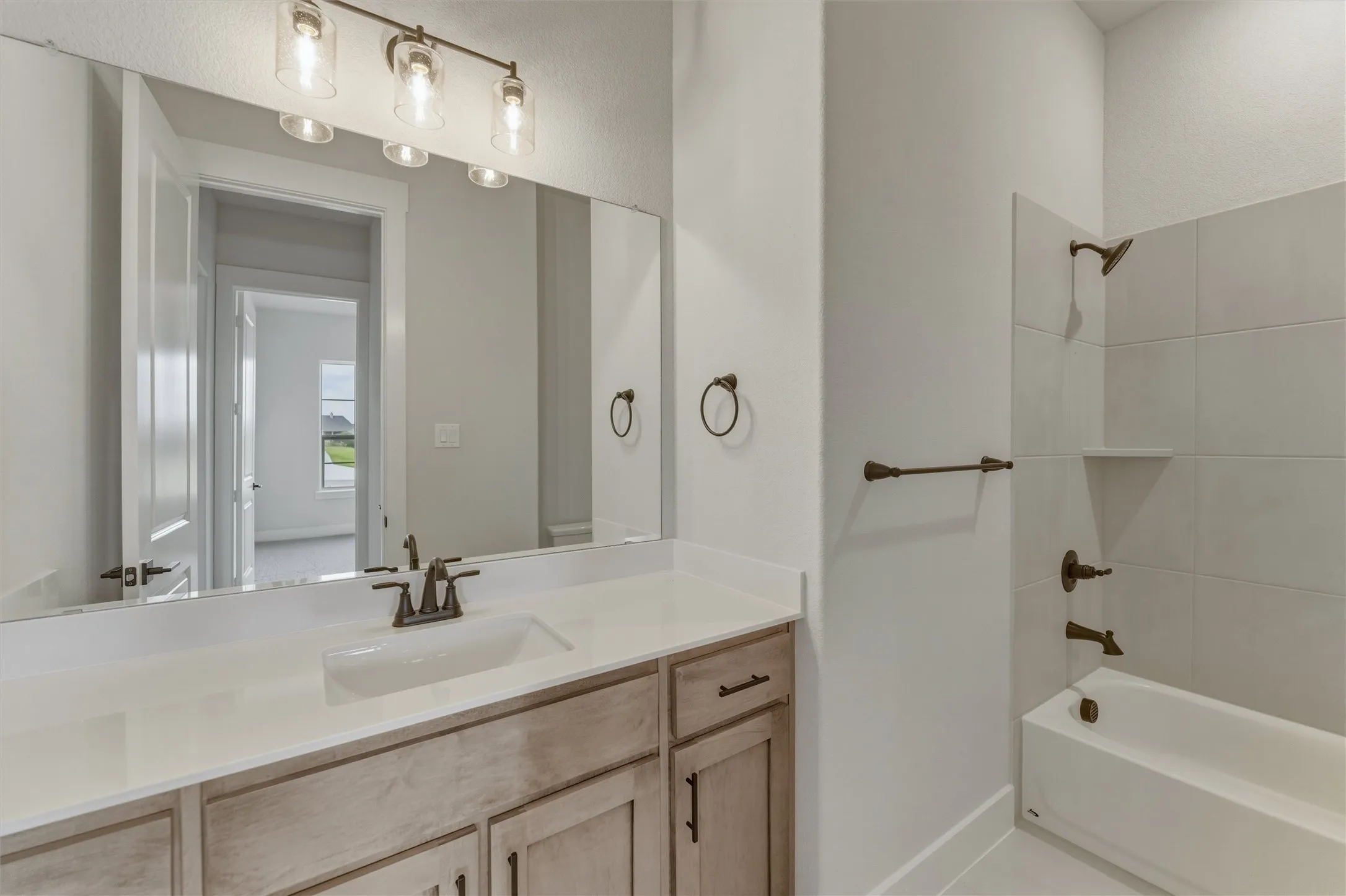 Bathroom featuring a light wood-finish vanity with a single basin, white countertop, and oil-rubbed bronze fixtures