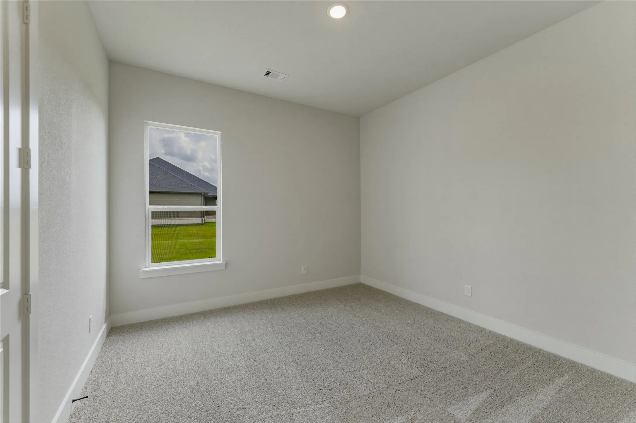 Carpeted room with a single window, white trim, and a recessed ceiling light