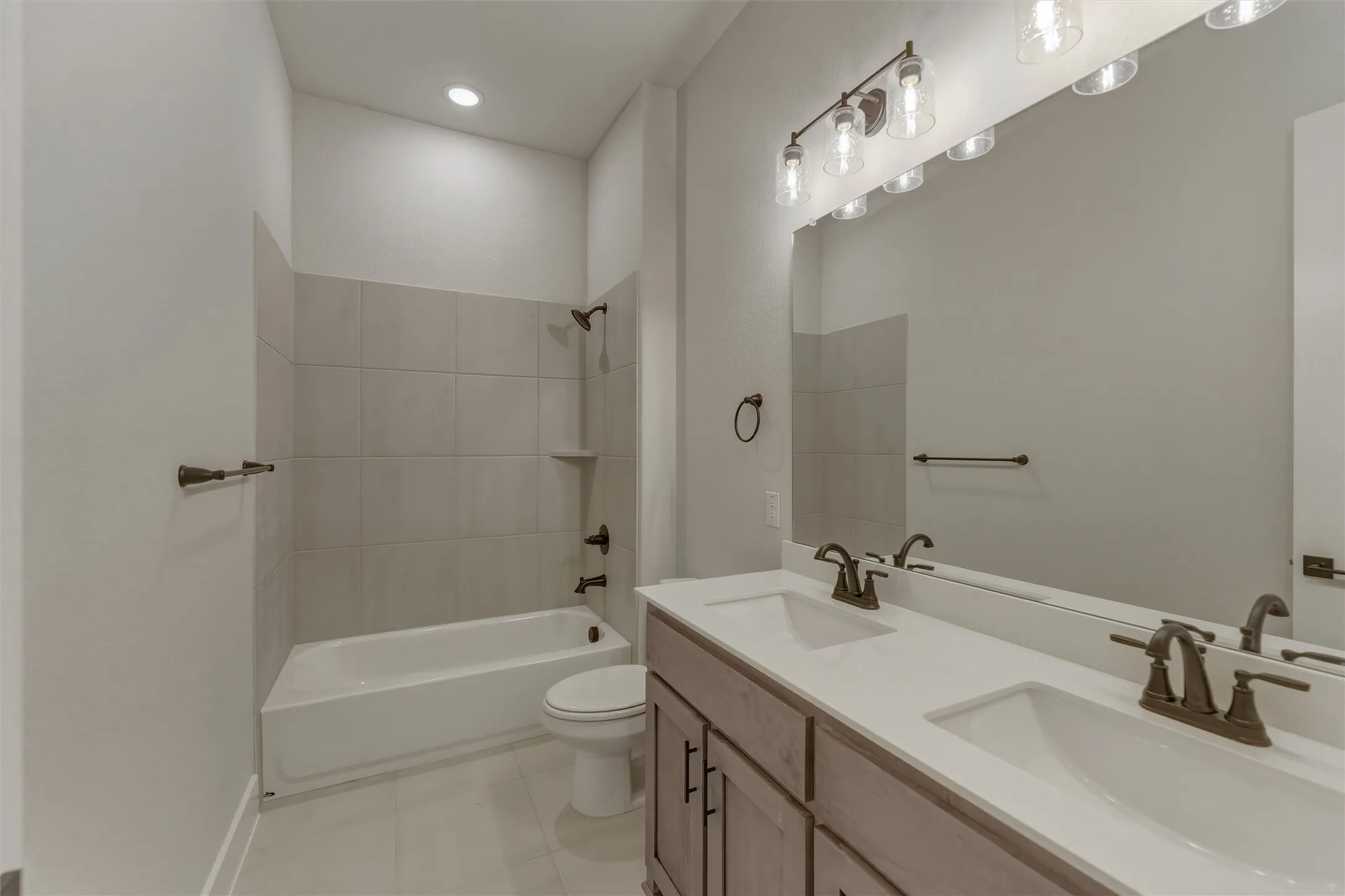 Bathroom featuring a double vanity with integrated sinks, a full-width mirror, and bronze-finish fixtures