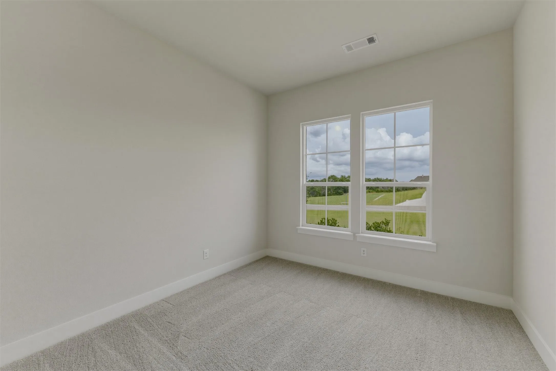 Interior room featuring light-toned walls, gray carpet flooring, white baseboards, and two multi-pane windows with white trim