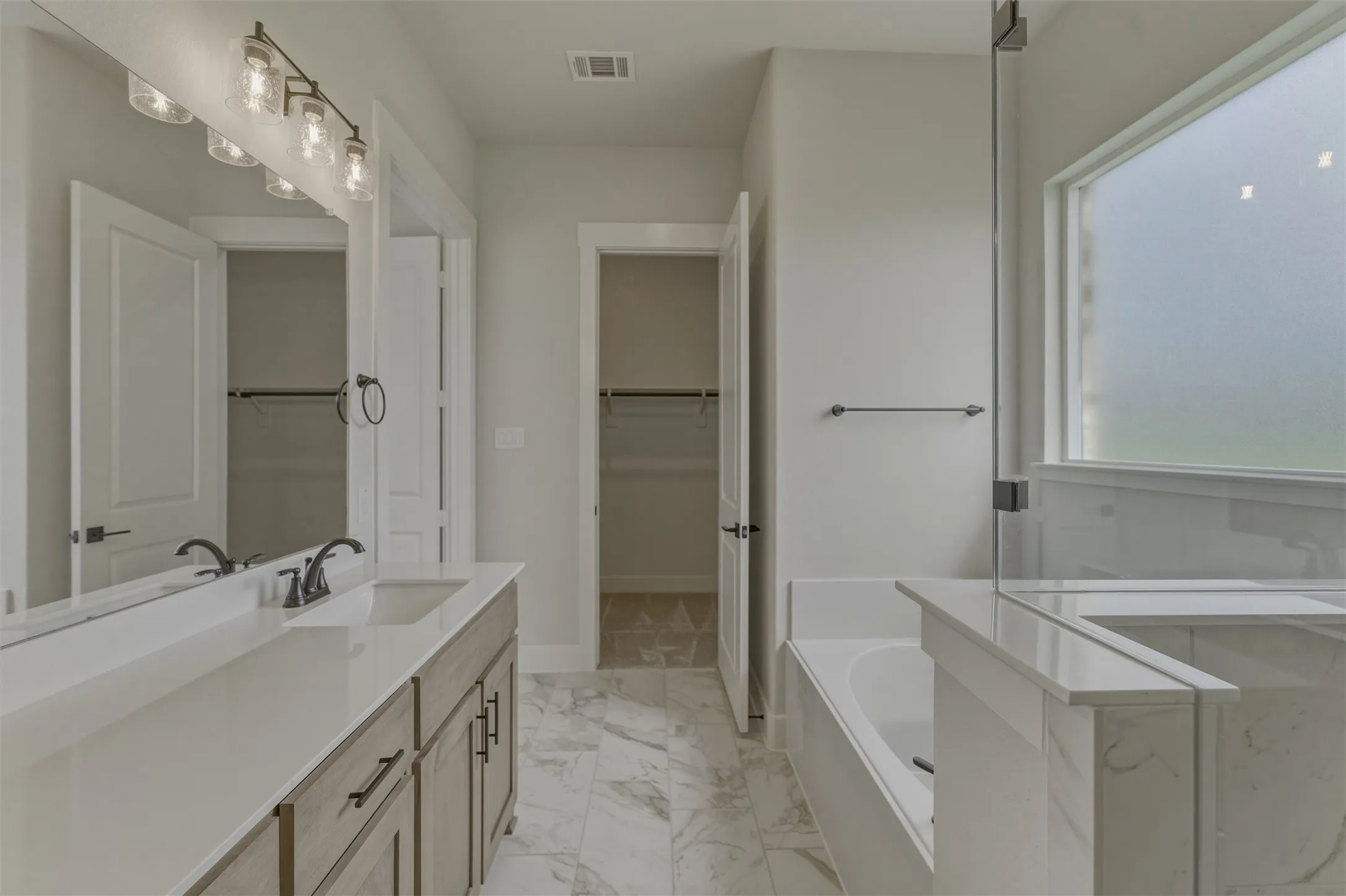Bathroom featuring a double vanity with stone countertops, undermount sinks, and matte black fixtures