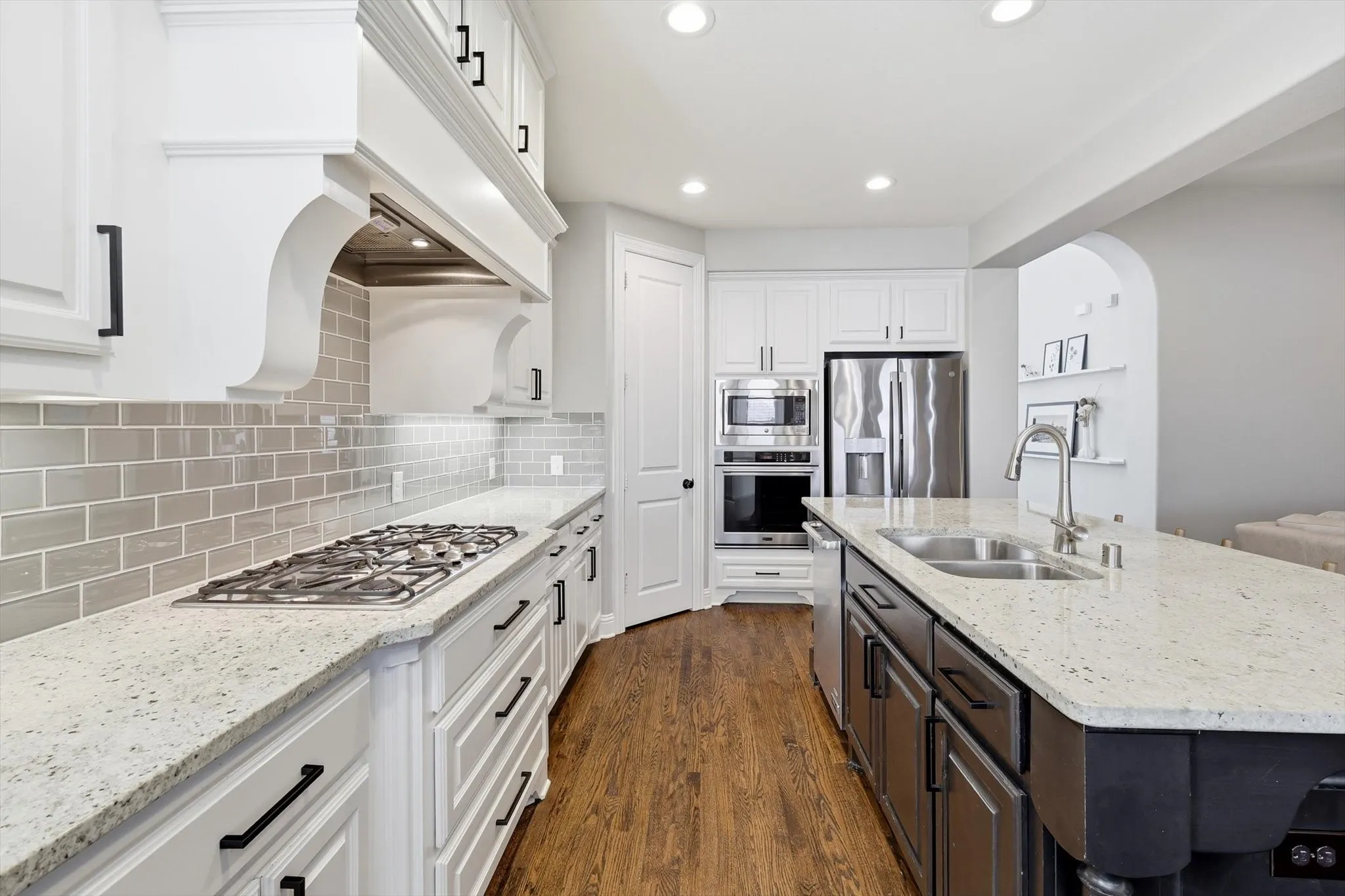 Two tone kitchen featuring light granite countertops, recessed lighting, wood flooring, two tone cabinets, and stainless steel appliances