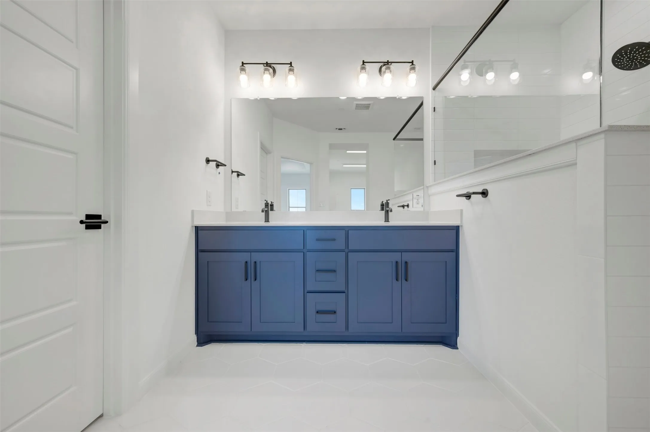 Dual vanity with a blue cabinet base, double sinks, and matte black fixtures