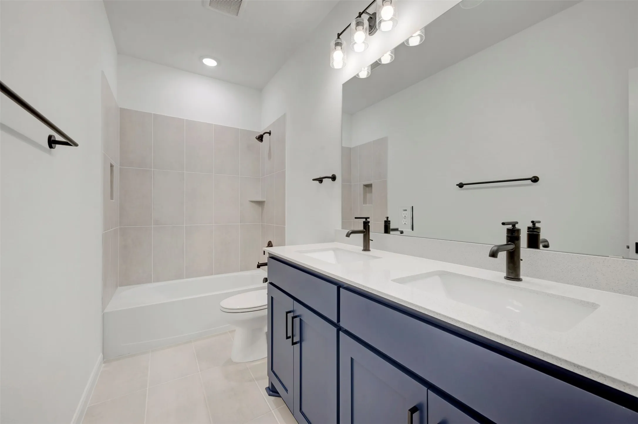 Bathroom featuring a double vanity with a deep blue cabinet, white countertop, and integrated sinks