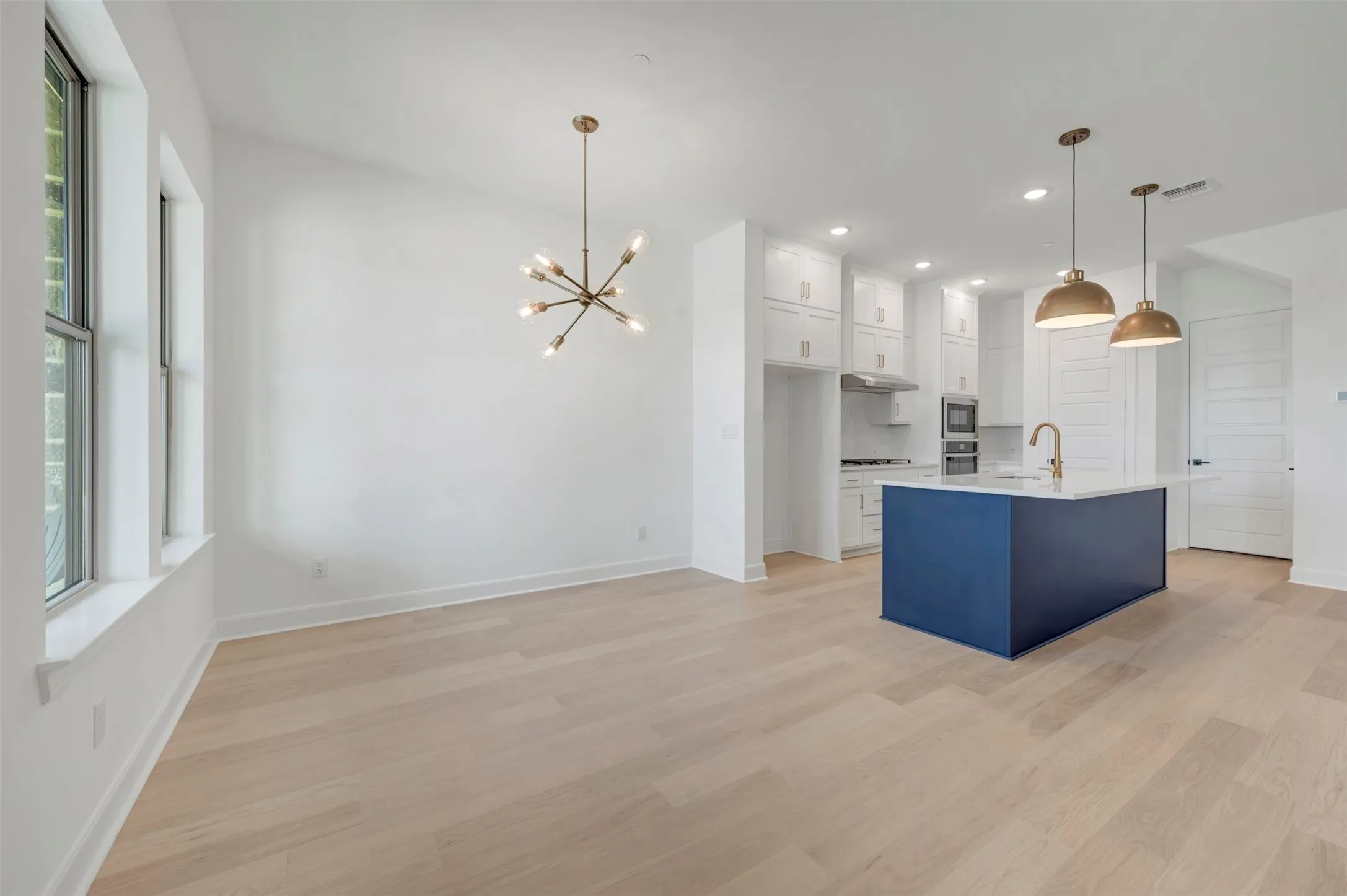 Open-concept living space featuring wood-finish flooring, a modern sputnik chandelier, and expansive windows