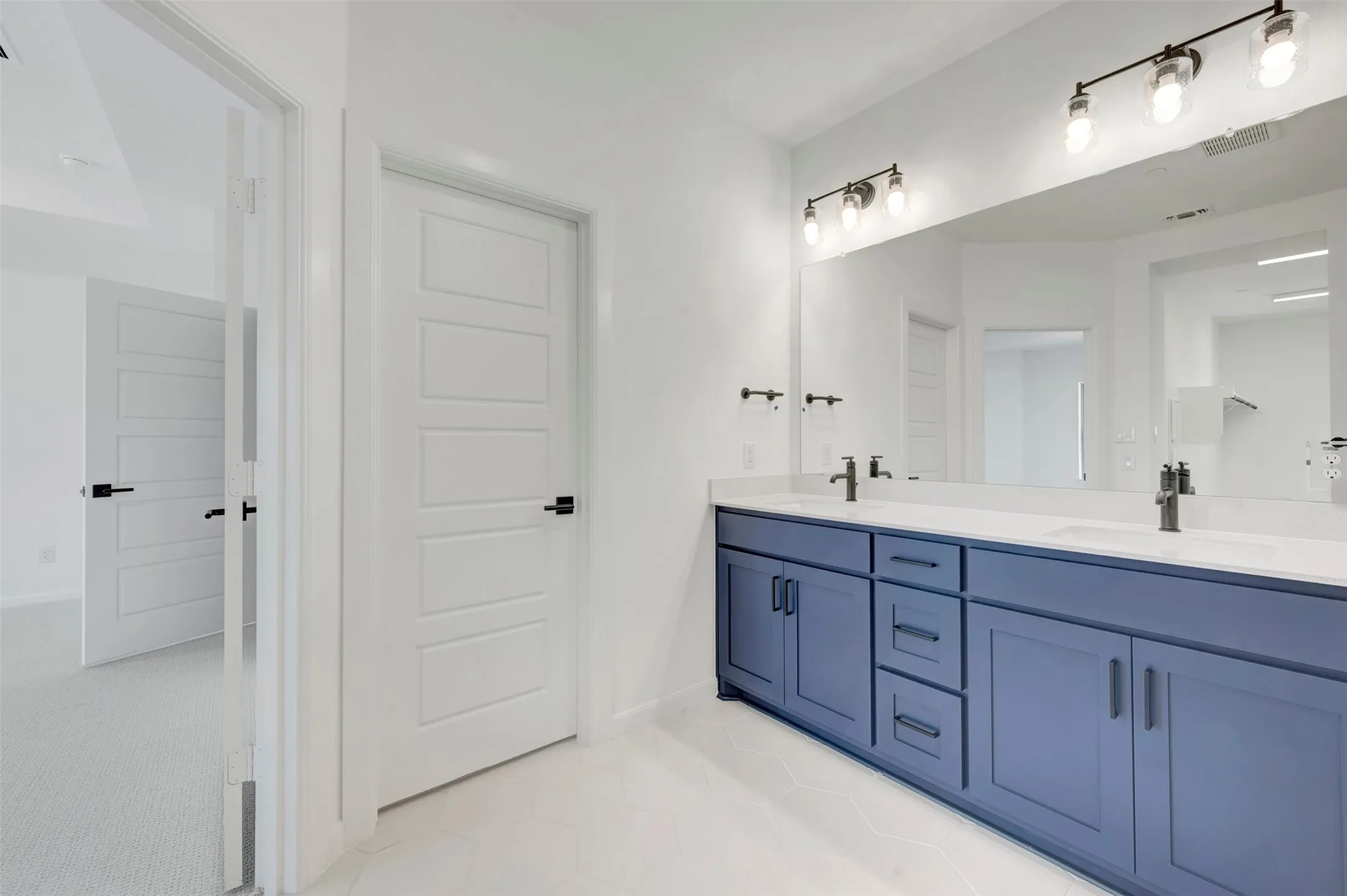Double vanity featuring a blue base cabinet with matte black hardware, white countertop, and dual undermount sinks