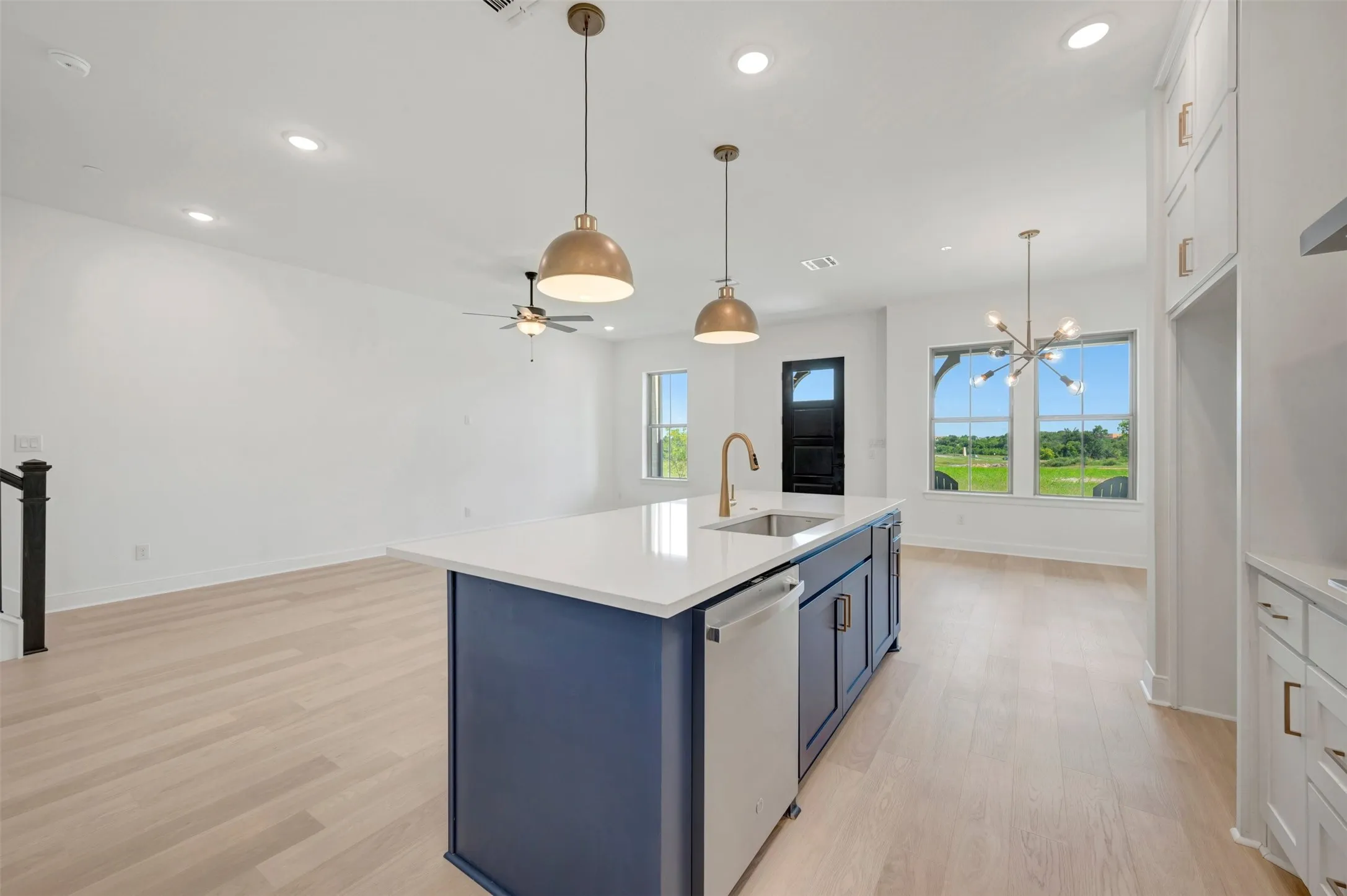Kitchen island with a white countertop and blue cabinetry featuring a built-in sink and dishwasher