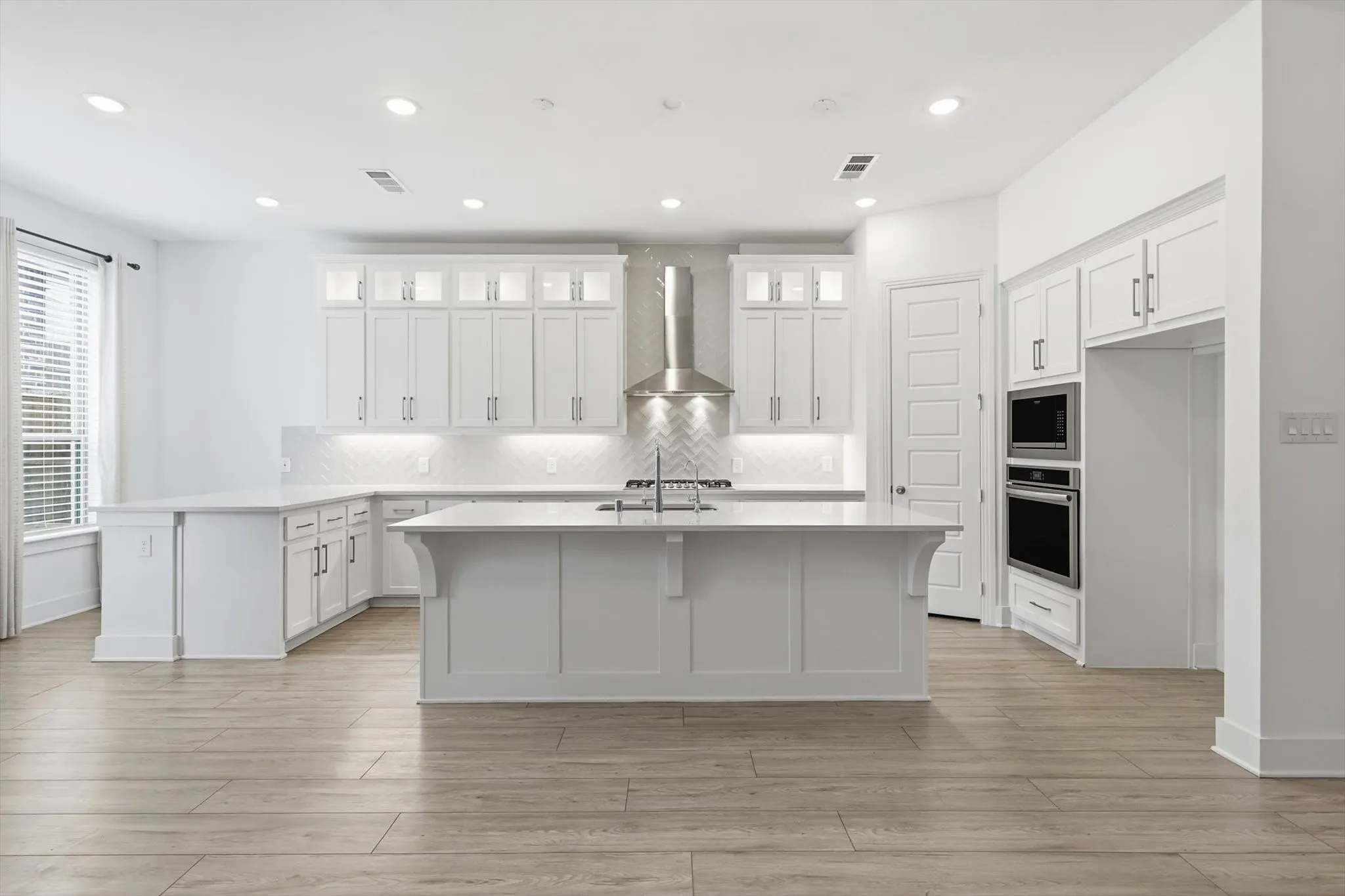 Marvelous Kitchen with white cabinets, SS appliacnes, Gas Cooktop, Decorative cabinets and massive amounts of counter space with island and additional seating on peninsula