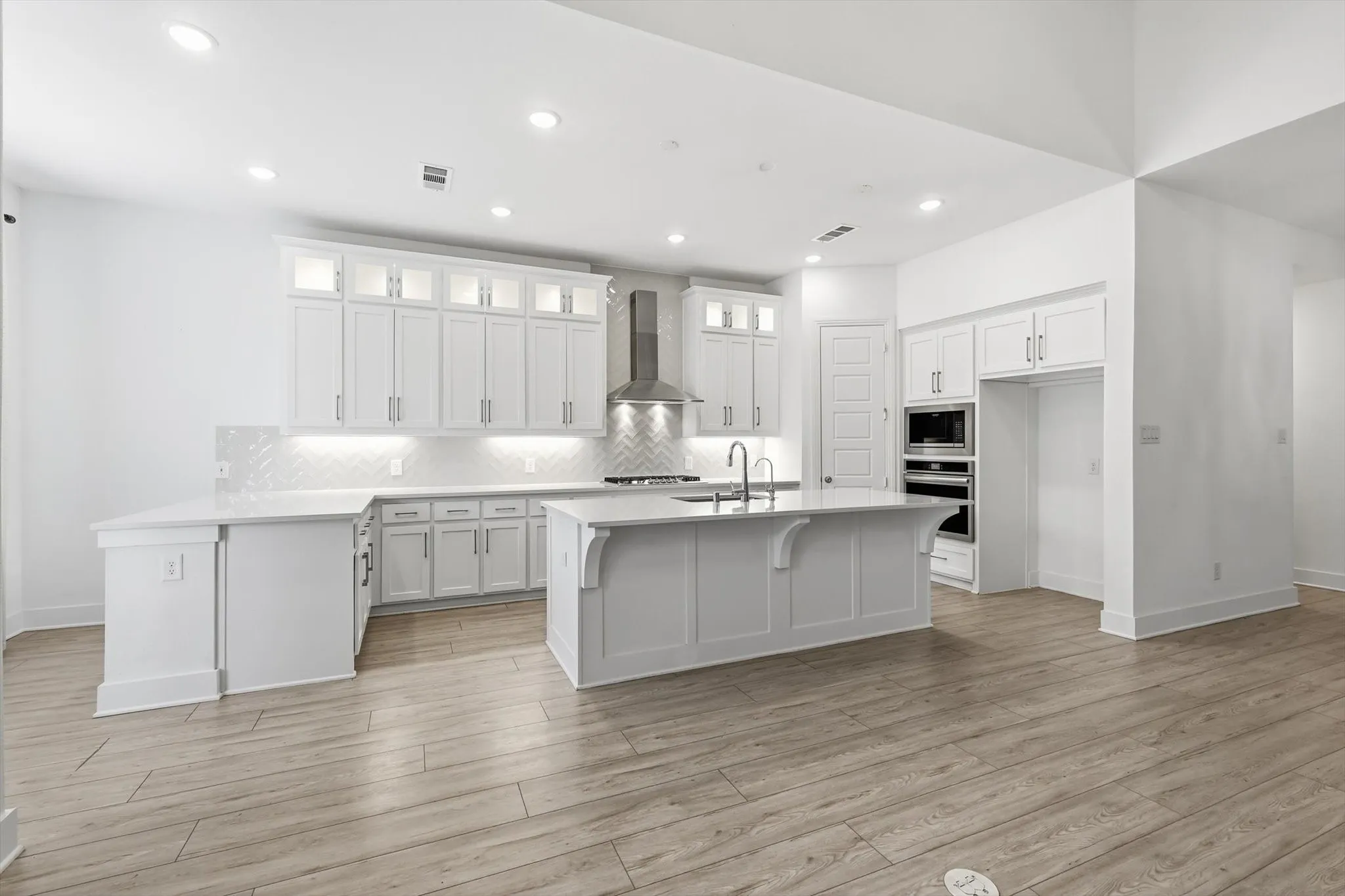 Marvelous Kitchen with white cabinets, SS appliacnes, Gas Cooktop, Decorative cabinets and massive amounts of counter space with island and additional seating on peninsula