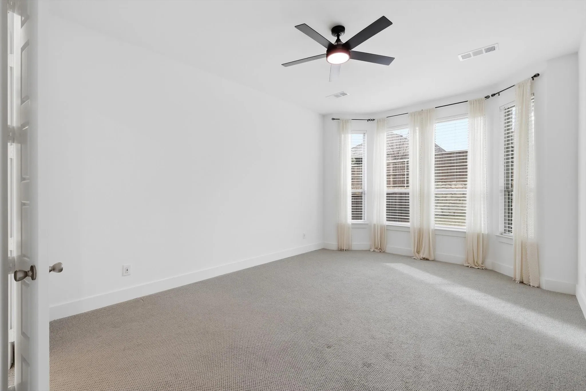 Large Primary on first level with bay windows, sitting room, fan and upgraded carpet