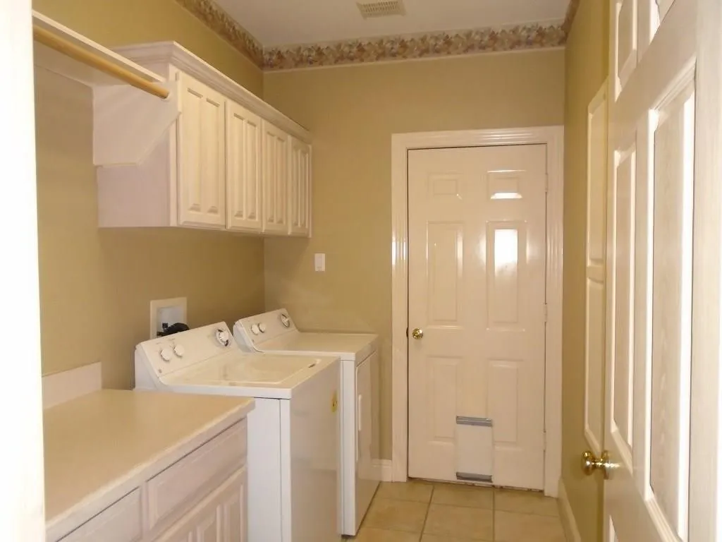 Laundry room with cabinet space, washer and clothes dryer, and light tile patterned floors