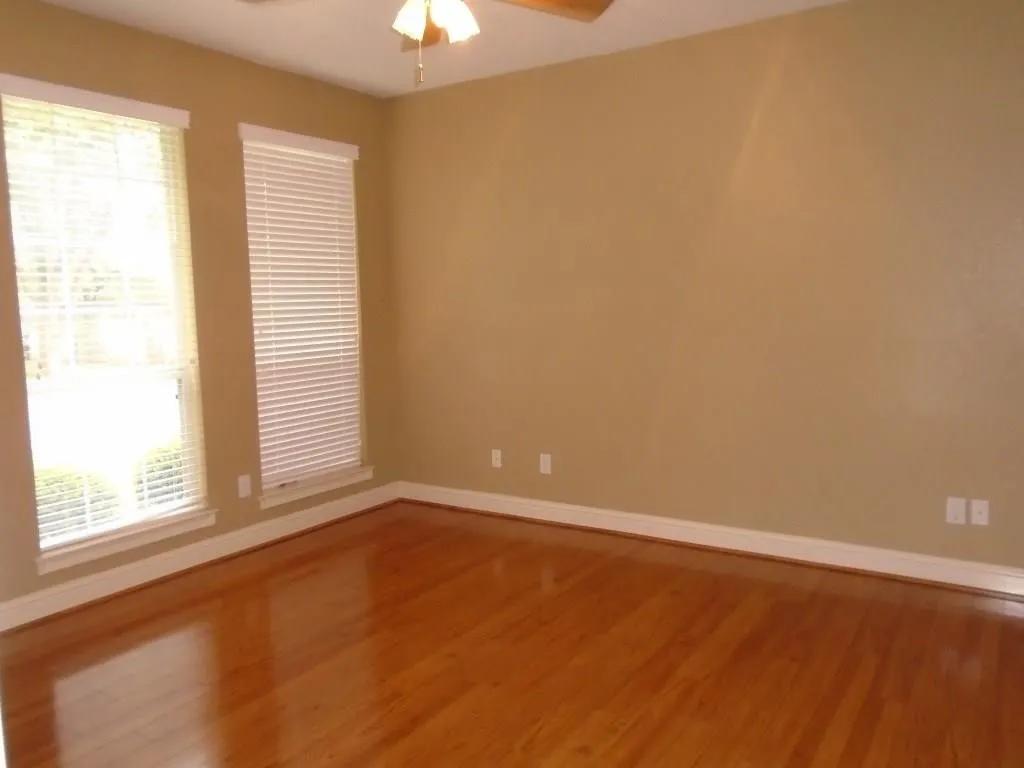 Spare room with wood finished floors and ceiling fan