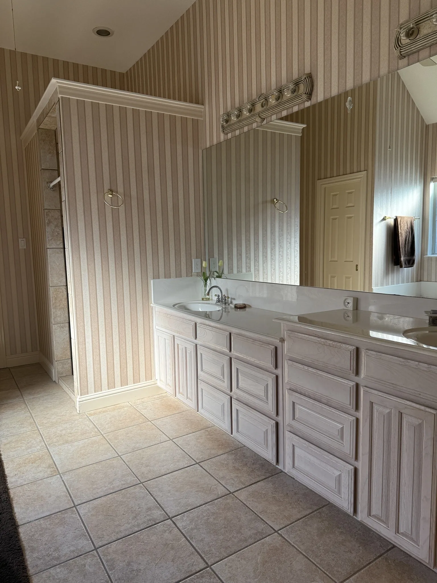 Double vanity featuring integrated sinks, light-toned cabinetry, and a large mirror