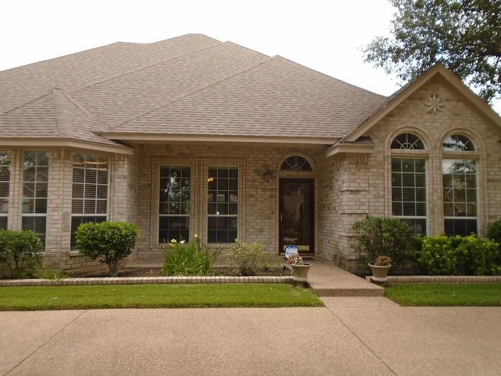 Single story home featuring a porch, brick siding, and a shingled roof