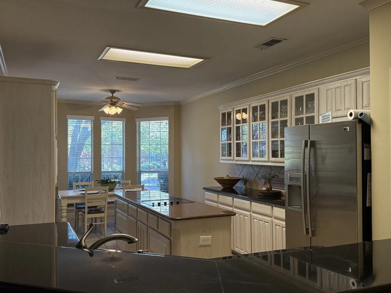 Kitchen featuring a large island with a cooktop, granite countertops, and white cabinetry
