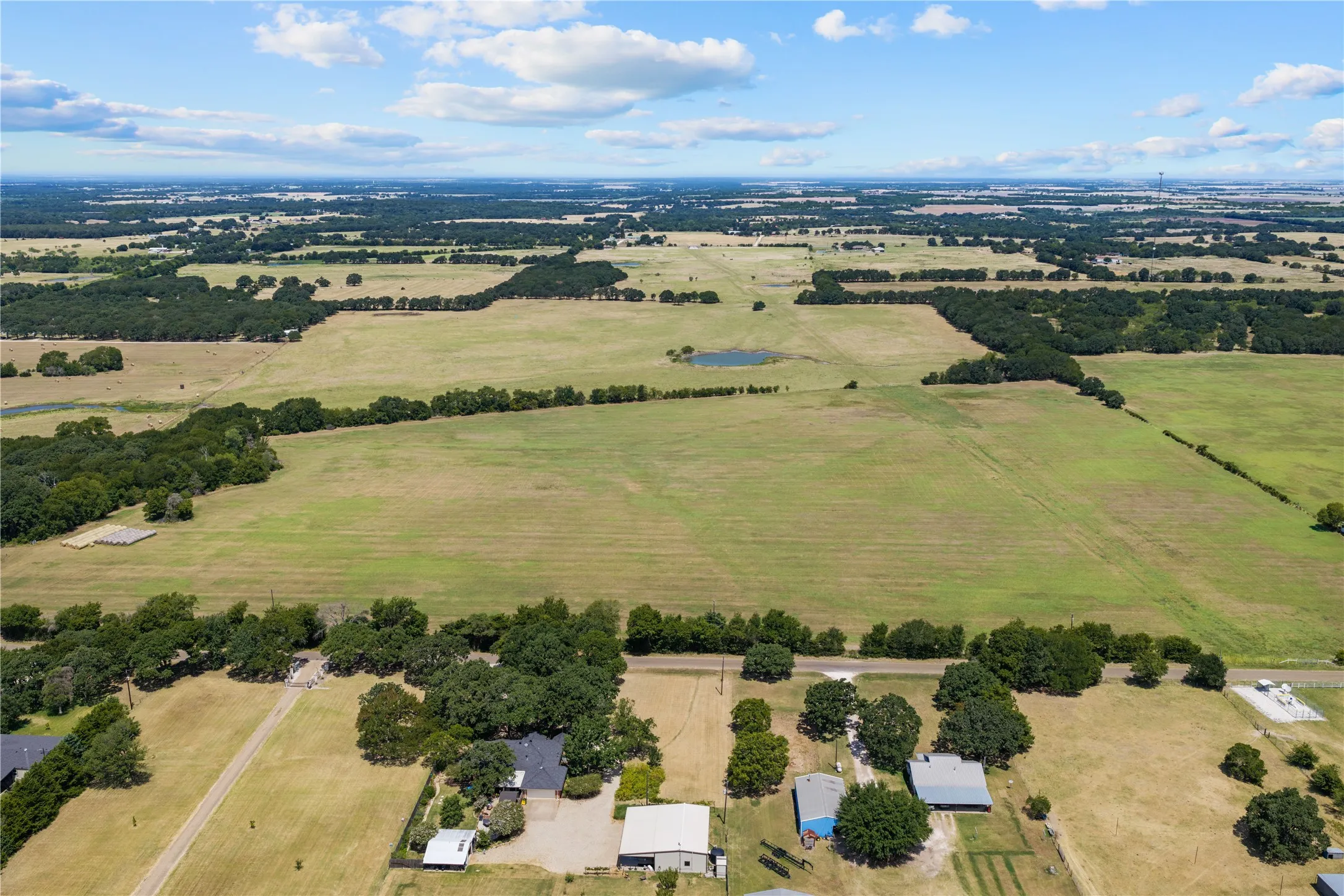 Expansive rural landscape featuring a mix of open fields and mature tree lines