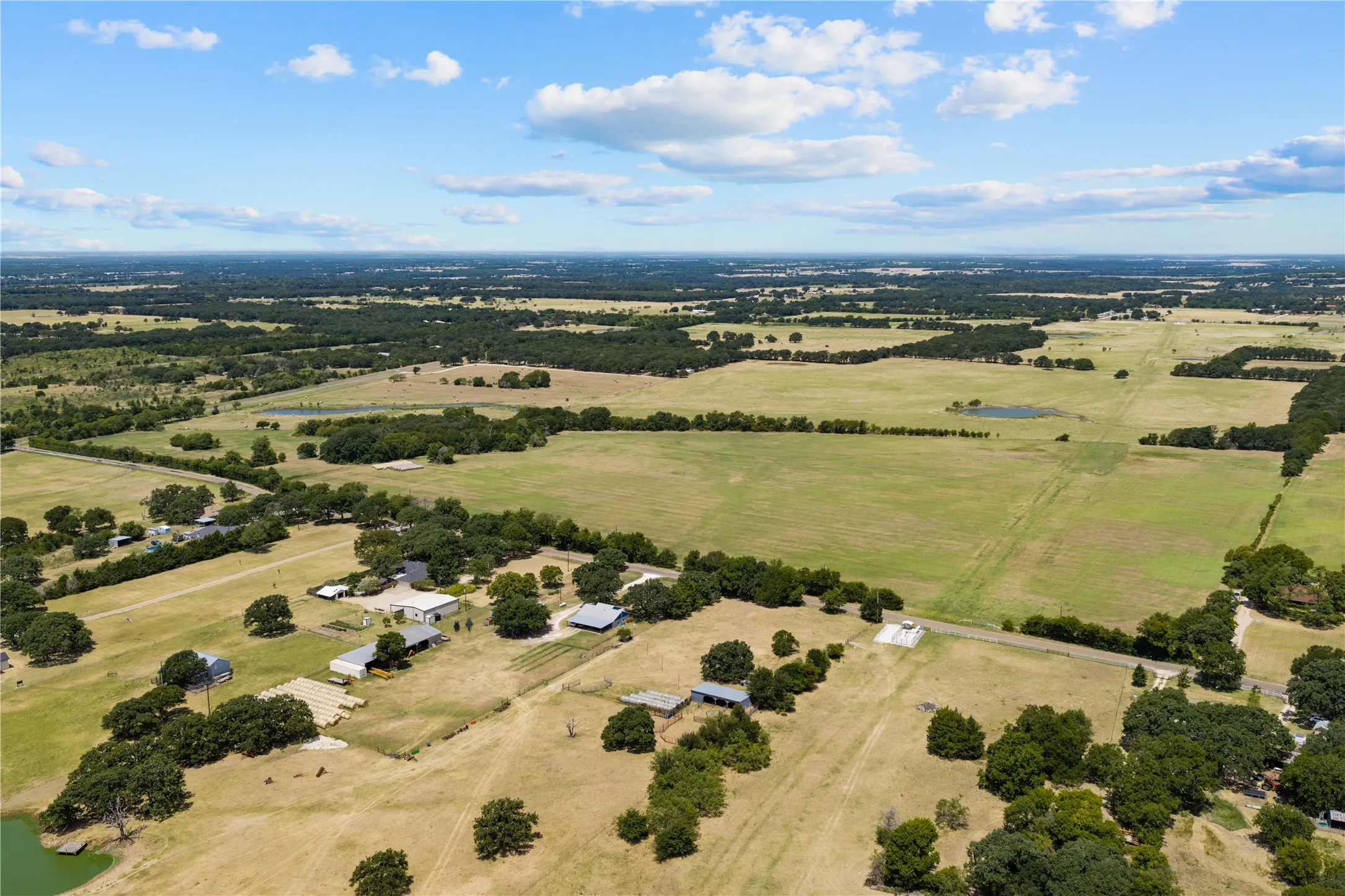 Expansive rural landscape featuring multiple parcels of open land, scattered tree lines, and several residential structures