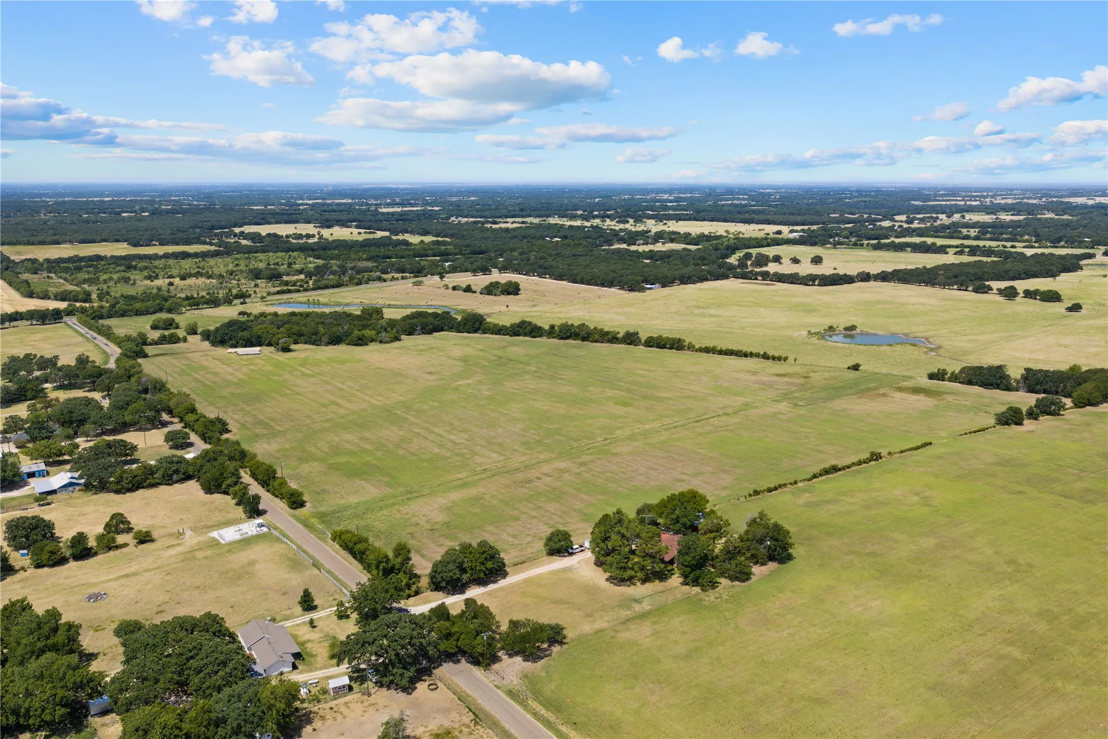 Expansive open land featuring a natural pond and mature trees