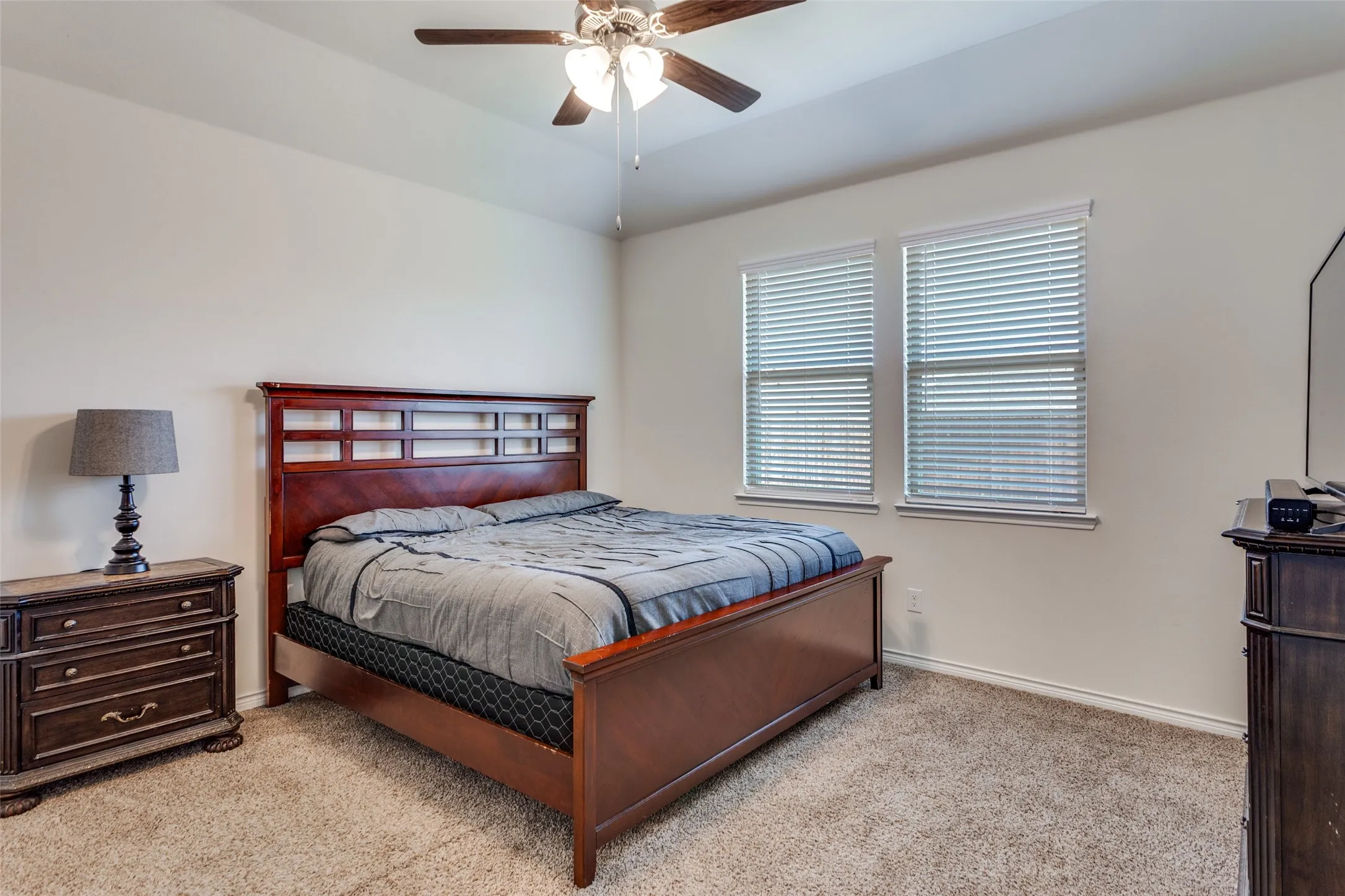 Bedroom with light colored carpet, ceiling fan, and vaulted ceiling