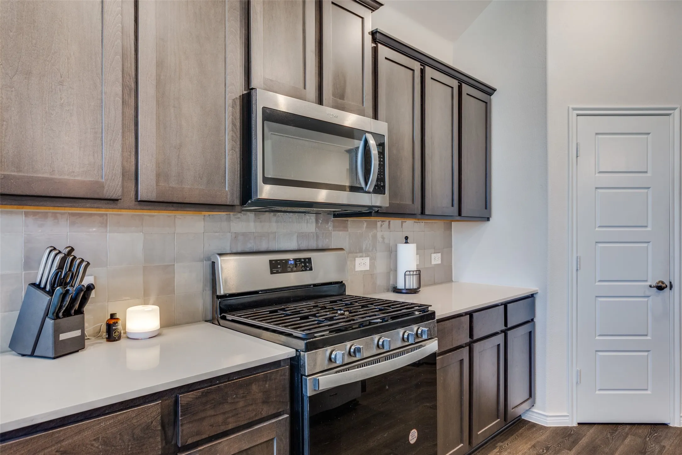 Kitchen featuring stainless steel appliances, decorative backsplash, dark wood finish cabinetry, and dark wood-type flooring