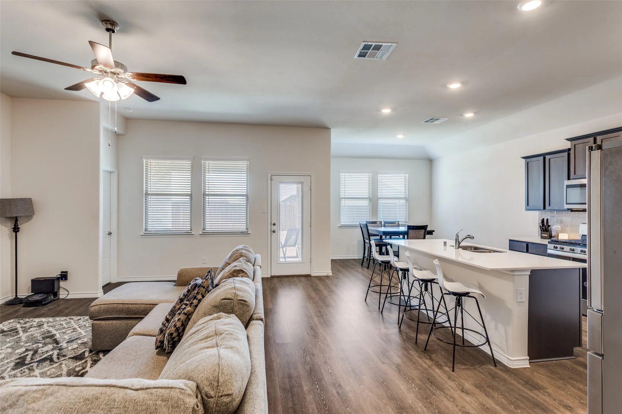 Living room with dark wood-type flooring, ceiling fan, and recessed lighting