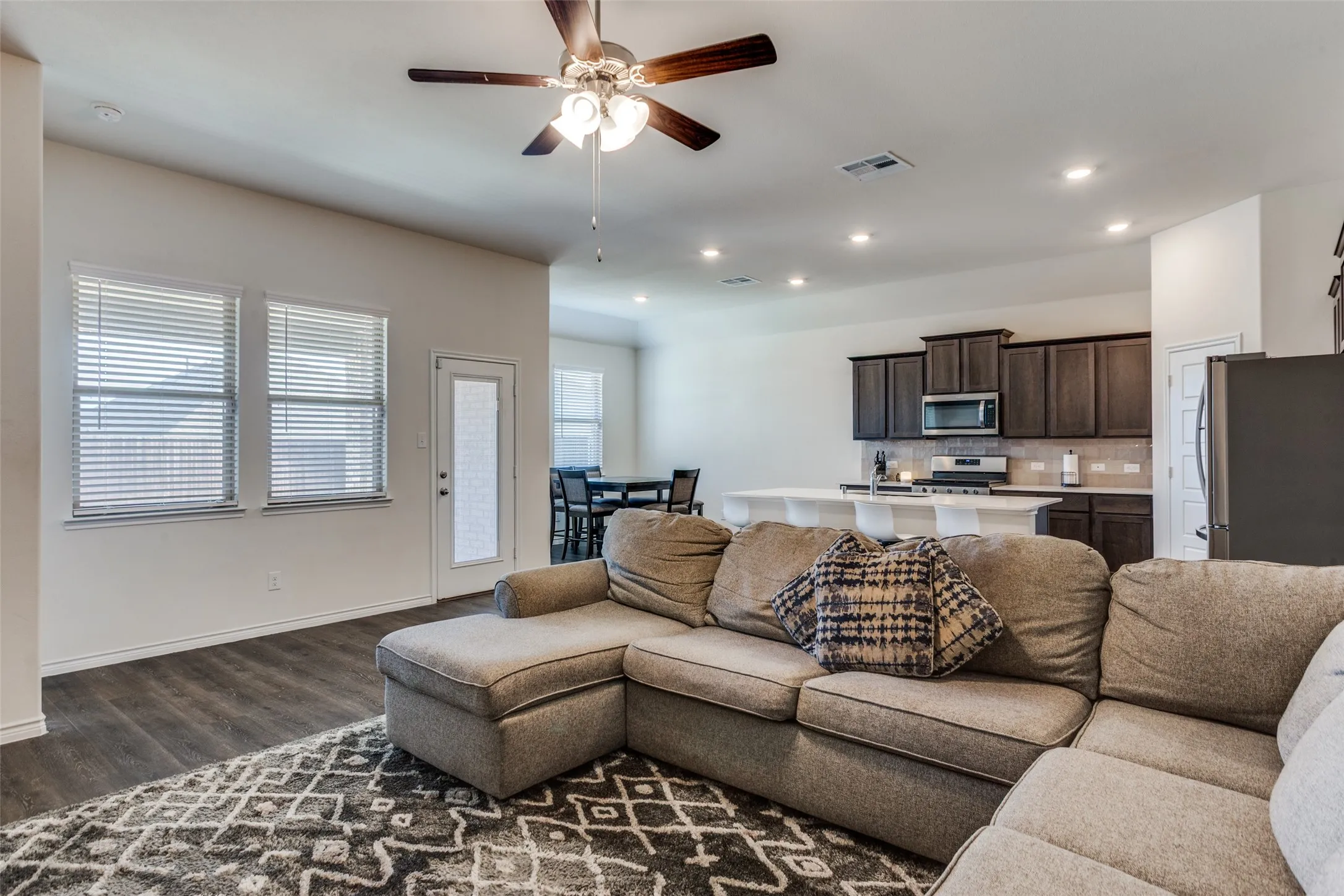 Living room with a ceiling fan, dark wood-style floors, and recessed lighting