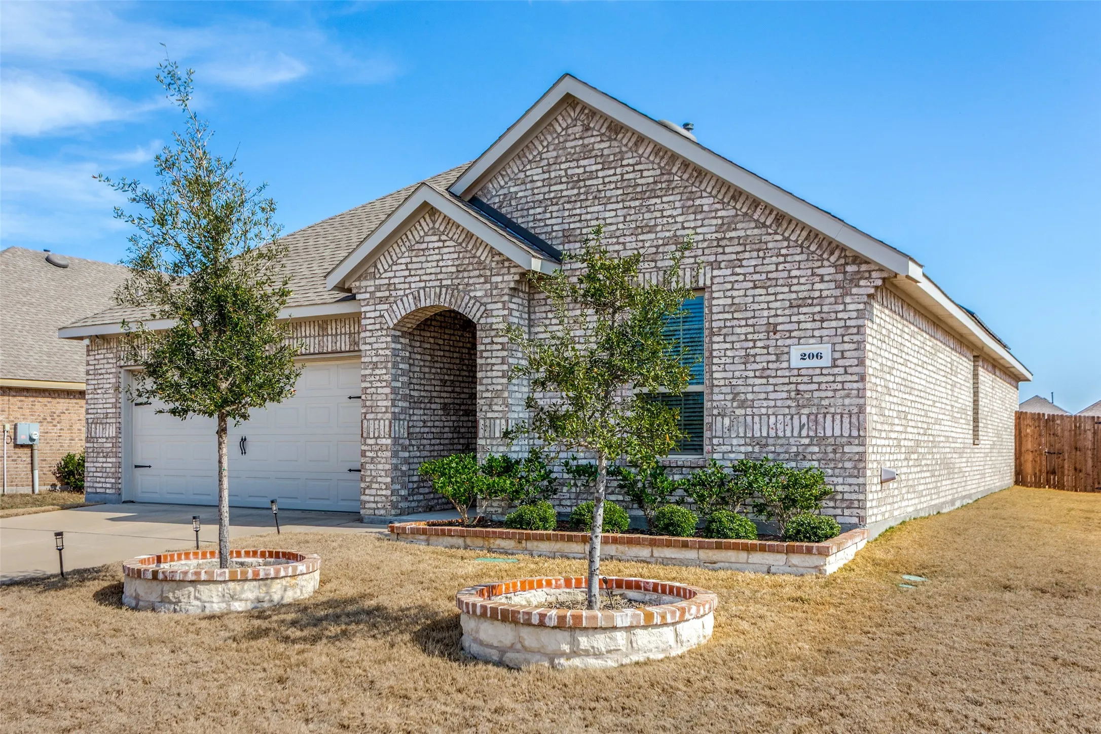 View of front of property with brick siding, an attached garage, driveway, and a front lawn