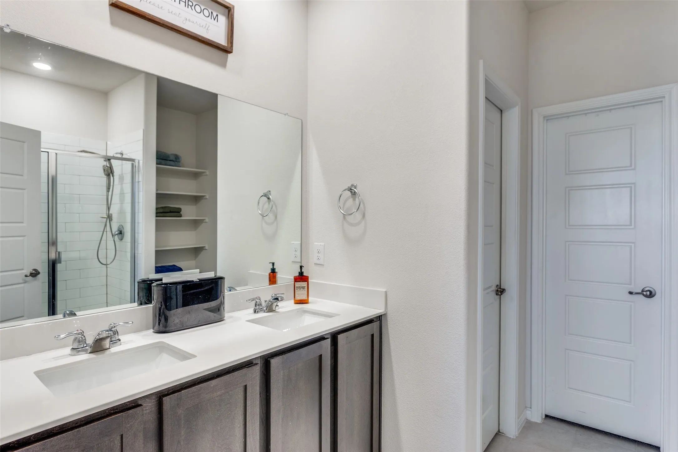 Bathroom featuring double vanity and a shower stall