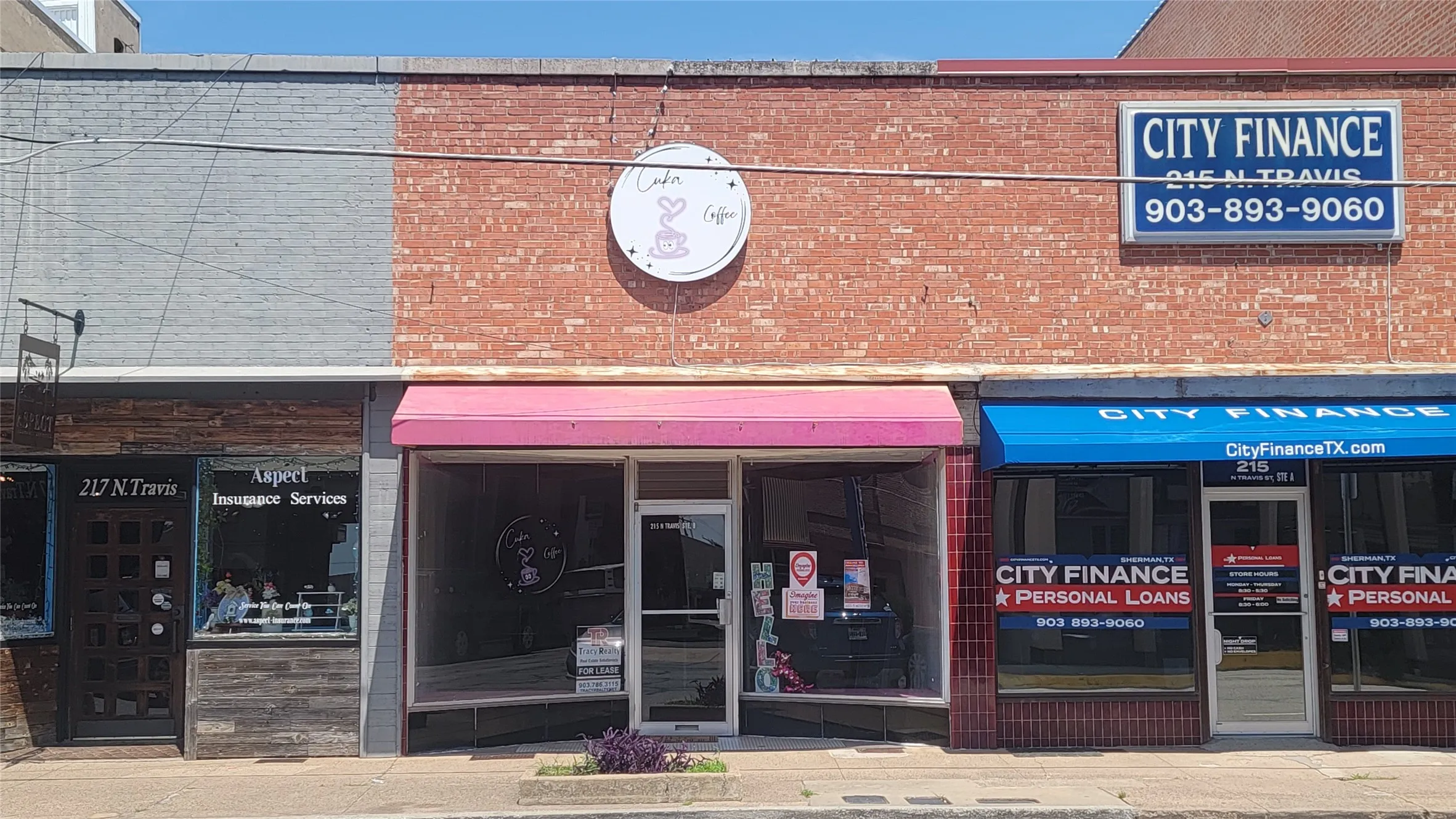 Commercial storefront featuring a red brick facade with a grey painted section