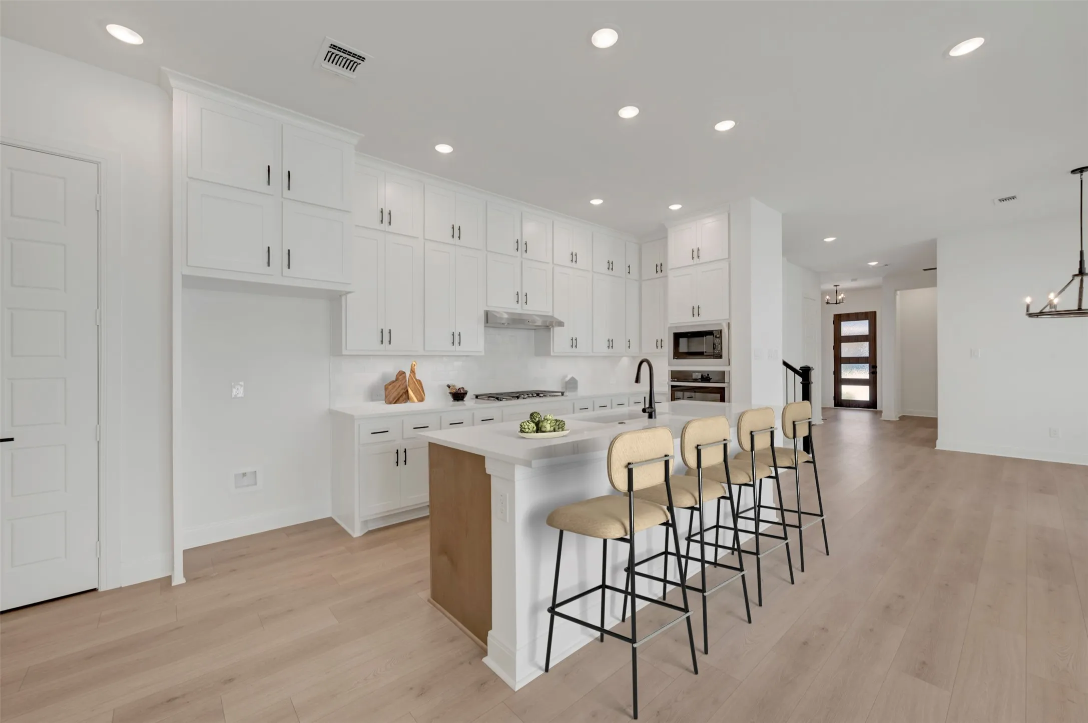 Contemporary kitchen featuring extensive white cabinetry, a large center island with seating, integrated appliances, and wood-finish flooring