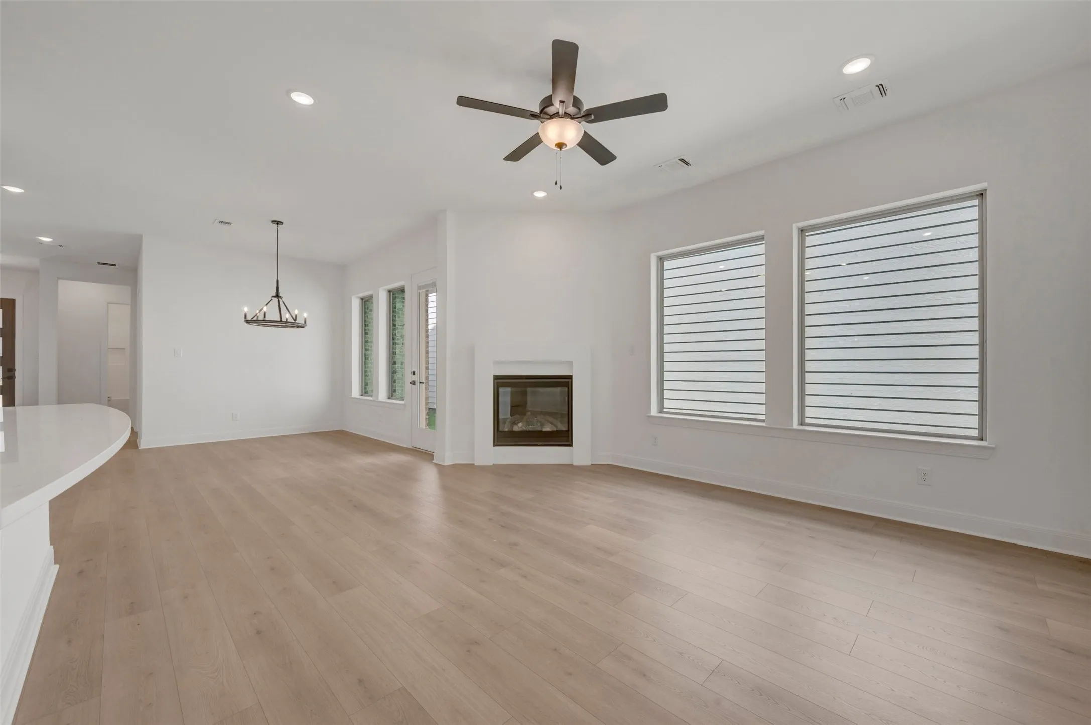 Spacious interior featuring wood-finish flooring, a contemporary fireplace, and abundant natural light from multiple windows