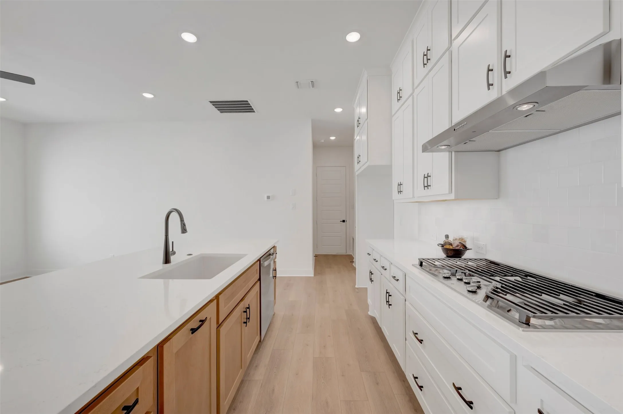 Kitchen featuring white shaker cabinetry, light wood-finish flooring, a stainless steel gas range, and recessed lighting