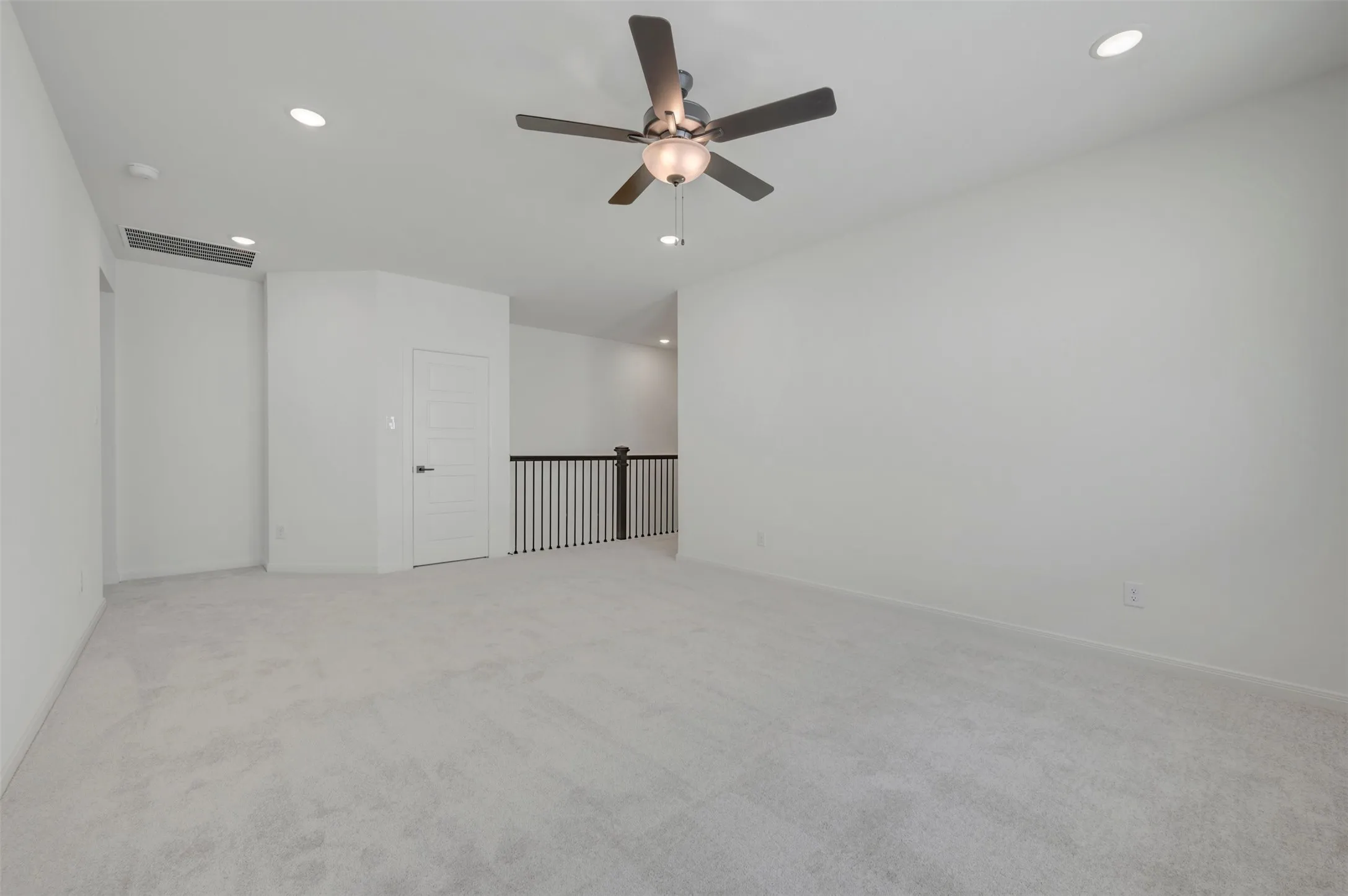 Recessed lighting, ceiling fan, light-toned carpeting, white walls, and a dark-toned banister