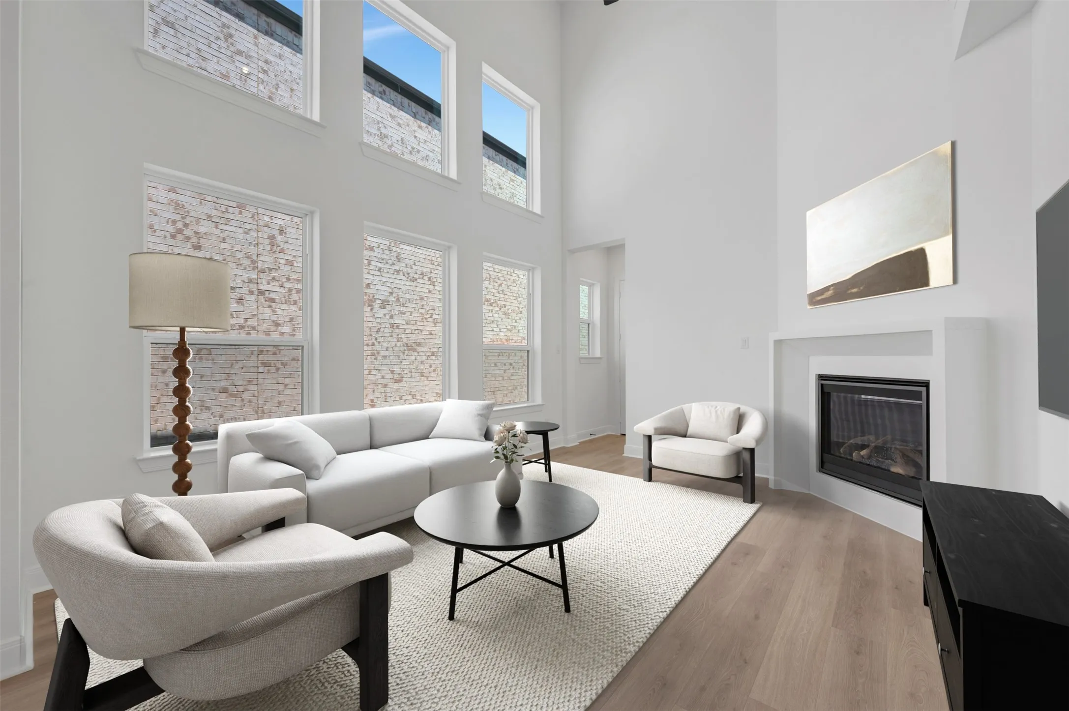 Double-height ceilings, a built-in fireplace, wood-finish flooring, and multiple windows