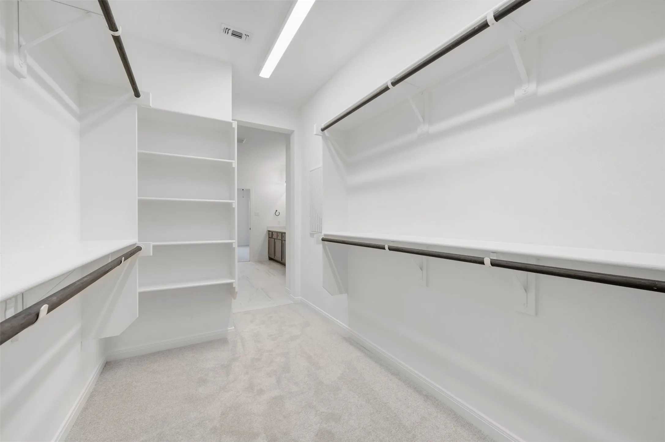 Spacious walk-in closet featuring floor-to-ceiling shelving, polished concrete flooring, and recessed lighting throughout