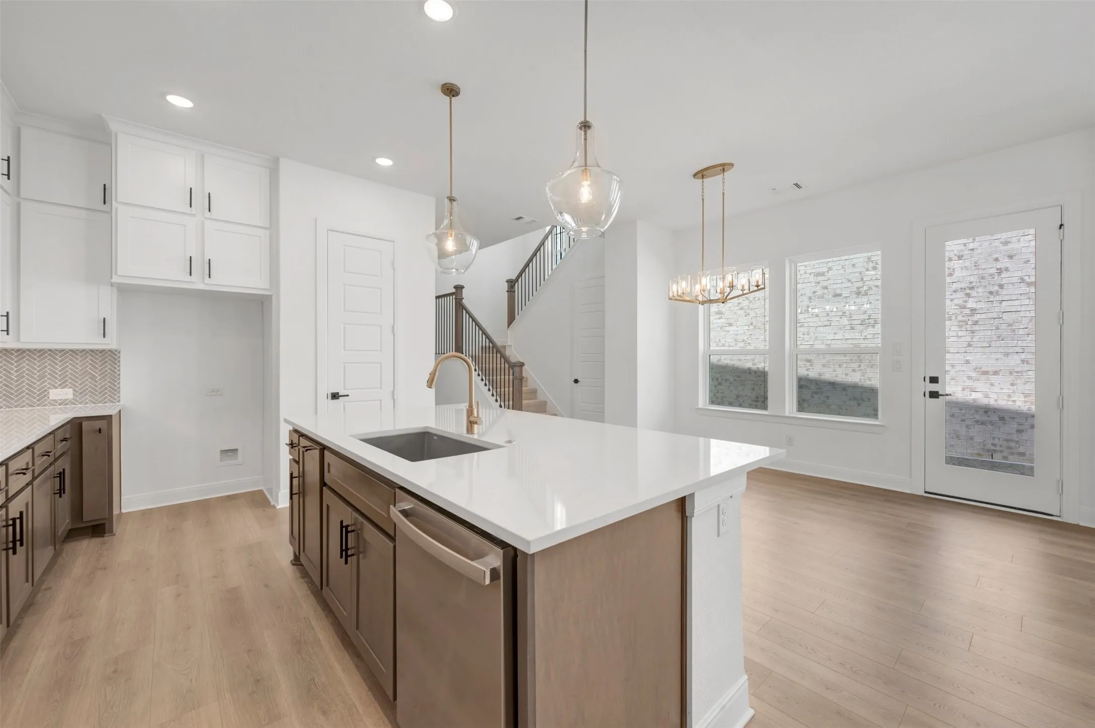 Kitchen featuring an island with a quartz countertop, a stainless steel sink, and a gold-tone faucet